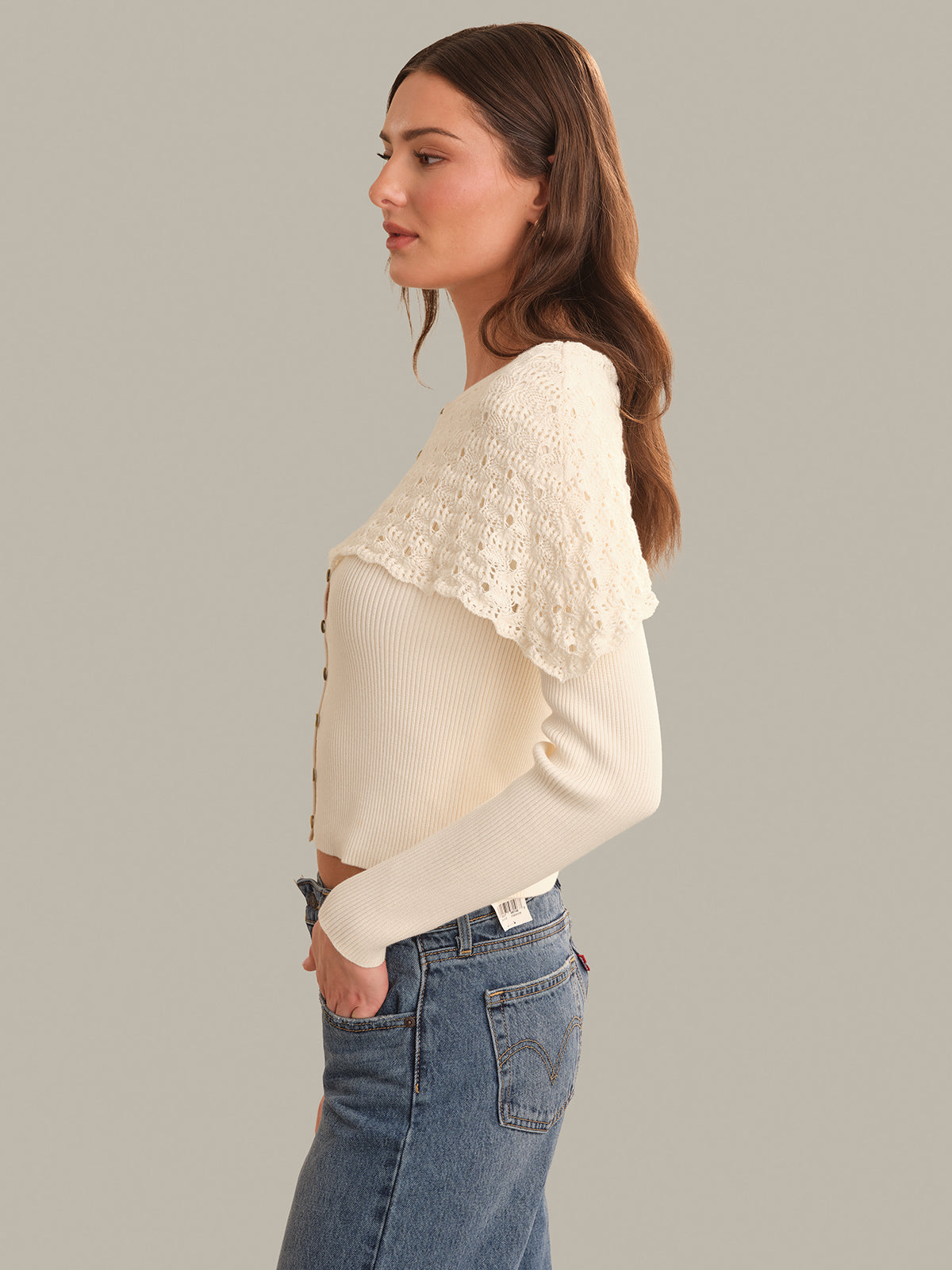 Woman wearing a cream sweater with a textured pattern on a gray background
