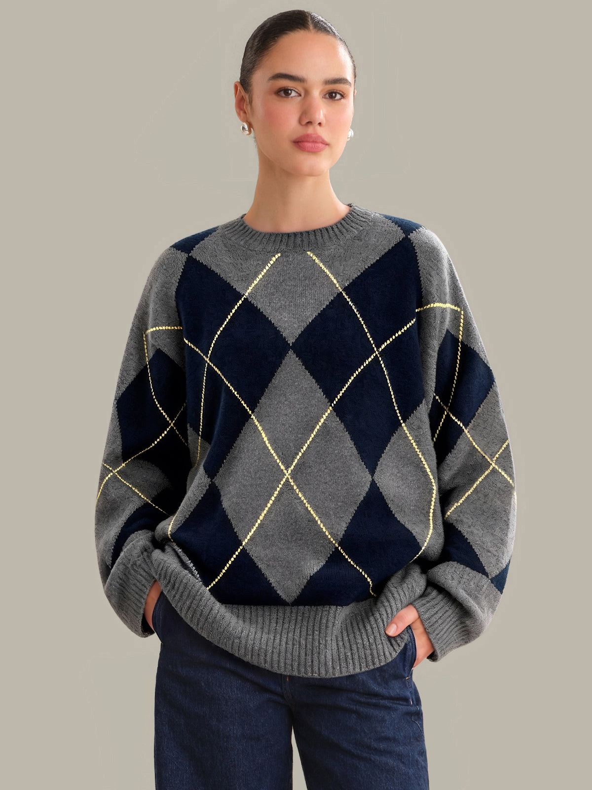 Person wearing a gray and navy argyle sweater against a plain background