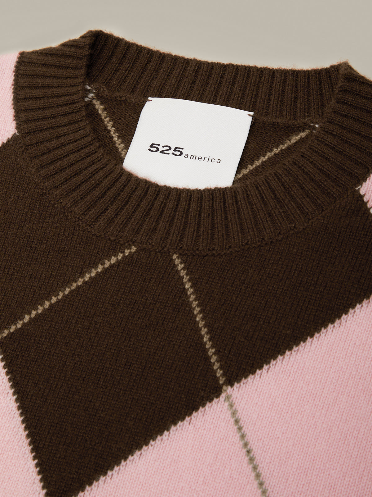 Brown and pink checkered sweater with a visible brand label on a neutral background