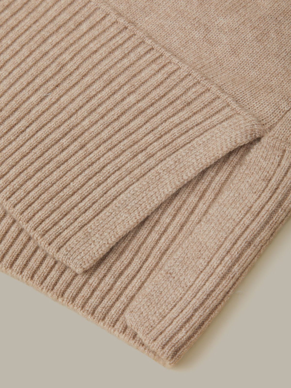 Close-up of a beige ribbed sweater on a light background