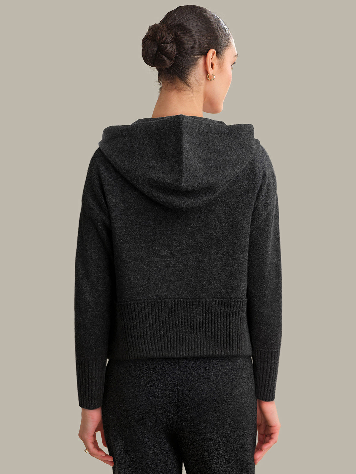 Person wearing a dark gray hoodie against a neutral background