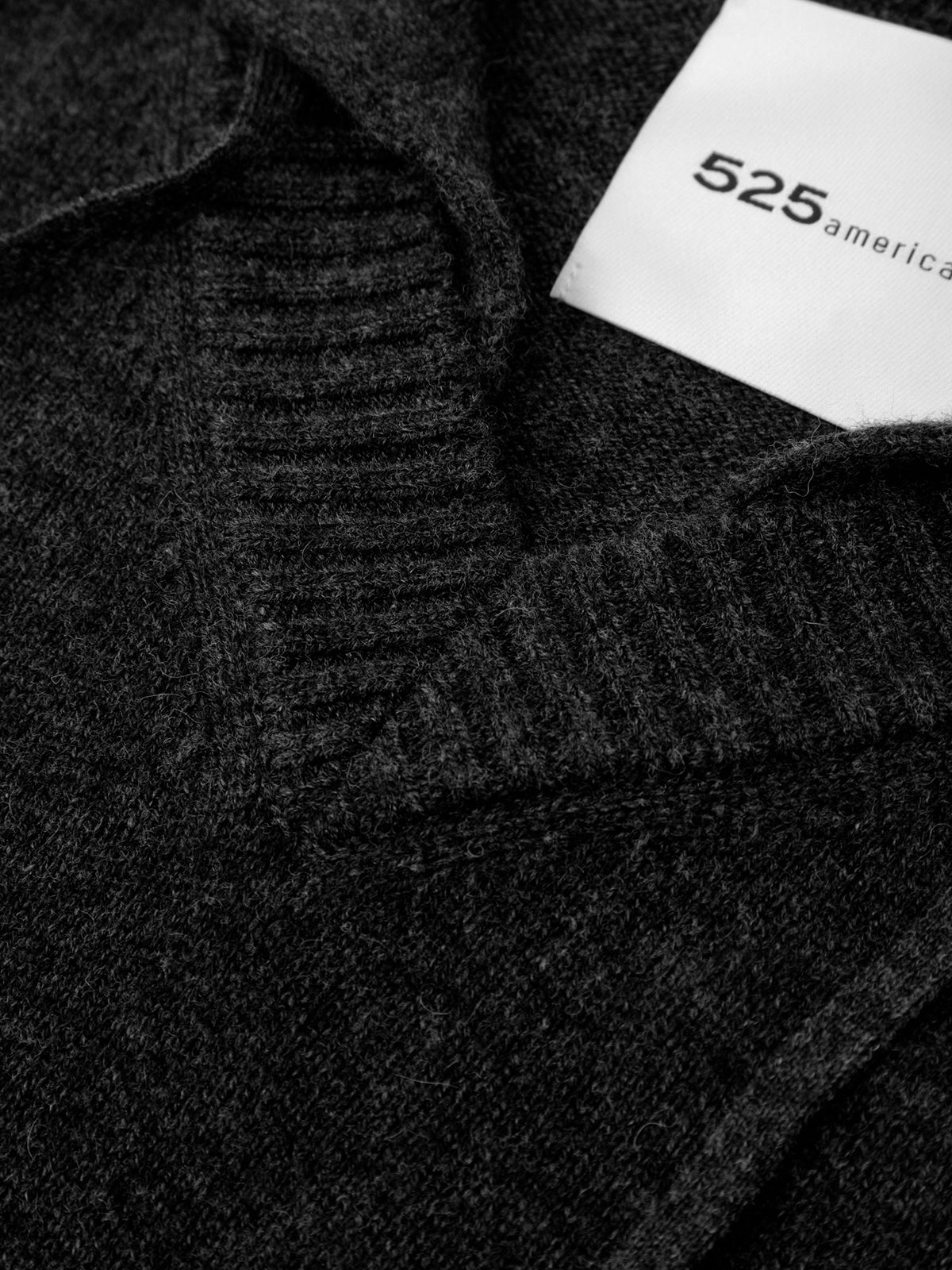 Close-up of a dark grey sweater with a visible brand label.