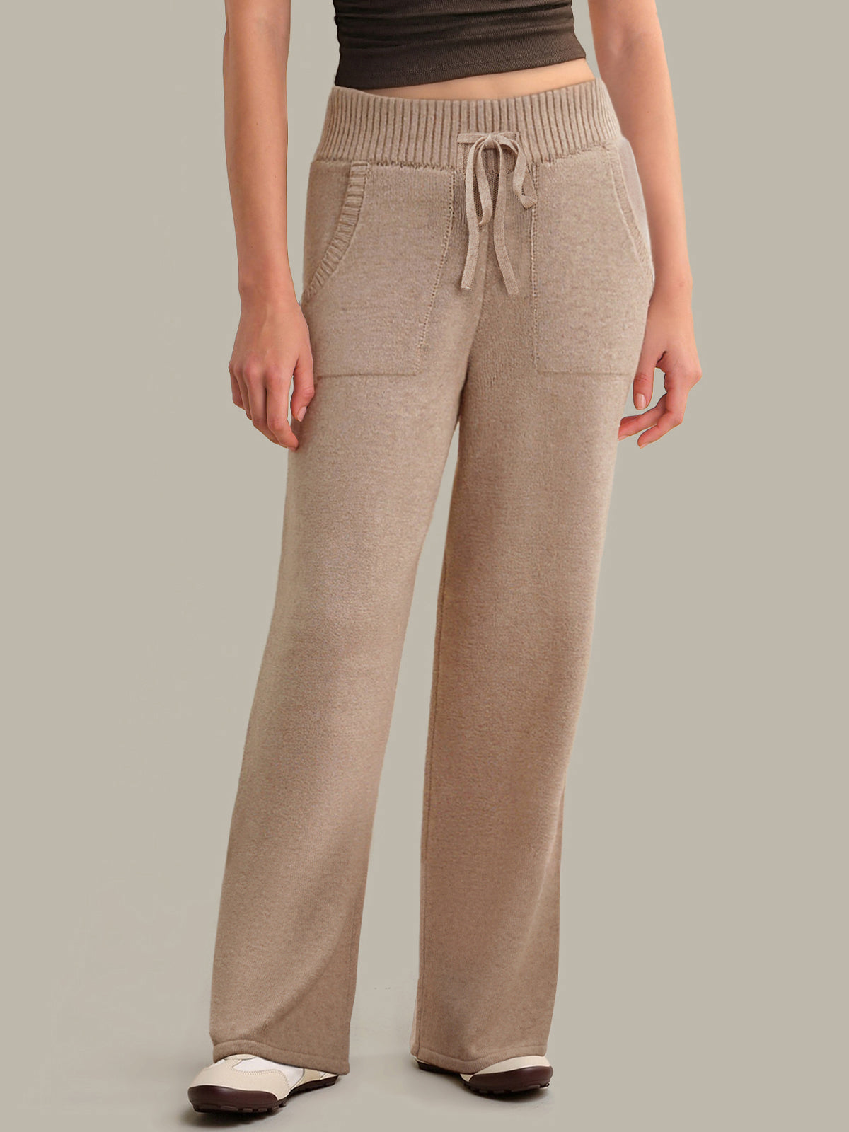Beige knitted pants worn by a person on a plain background