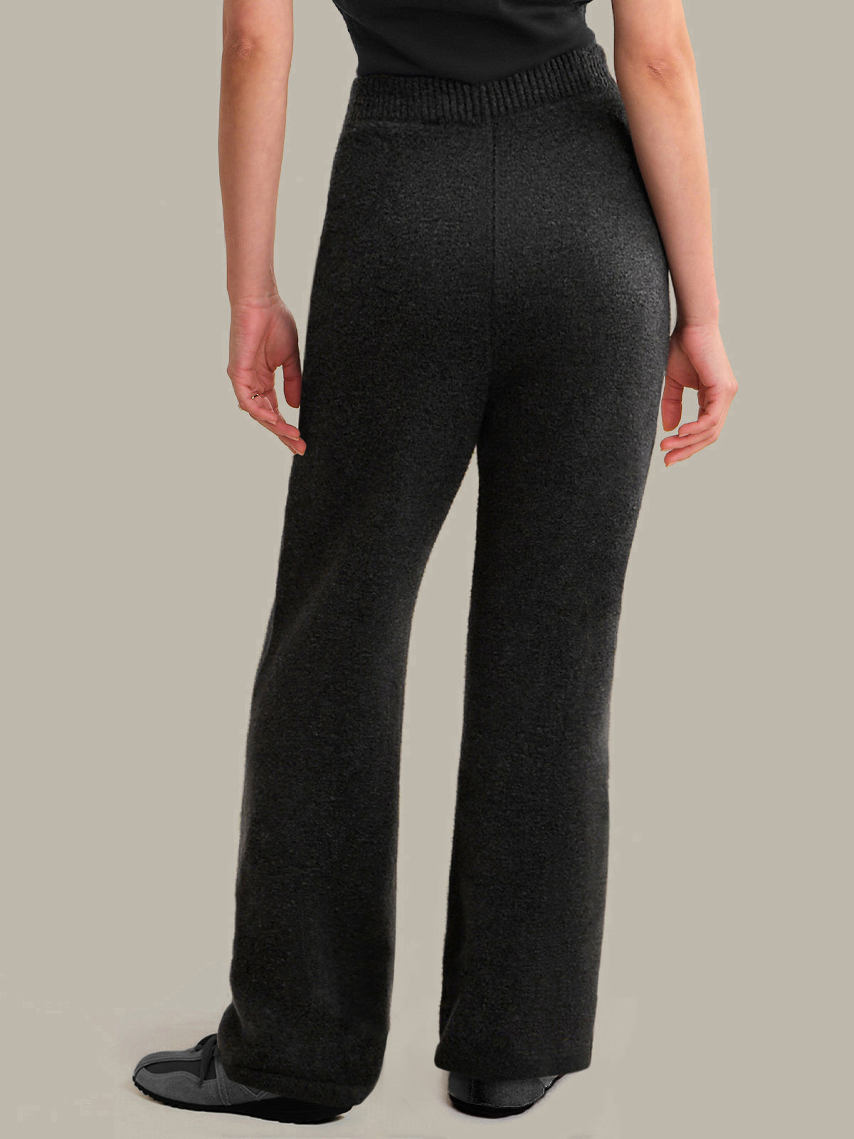 Dark gray knitted pants worn by a person on a neutral background