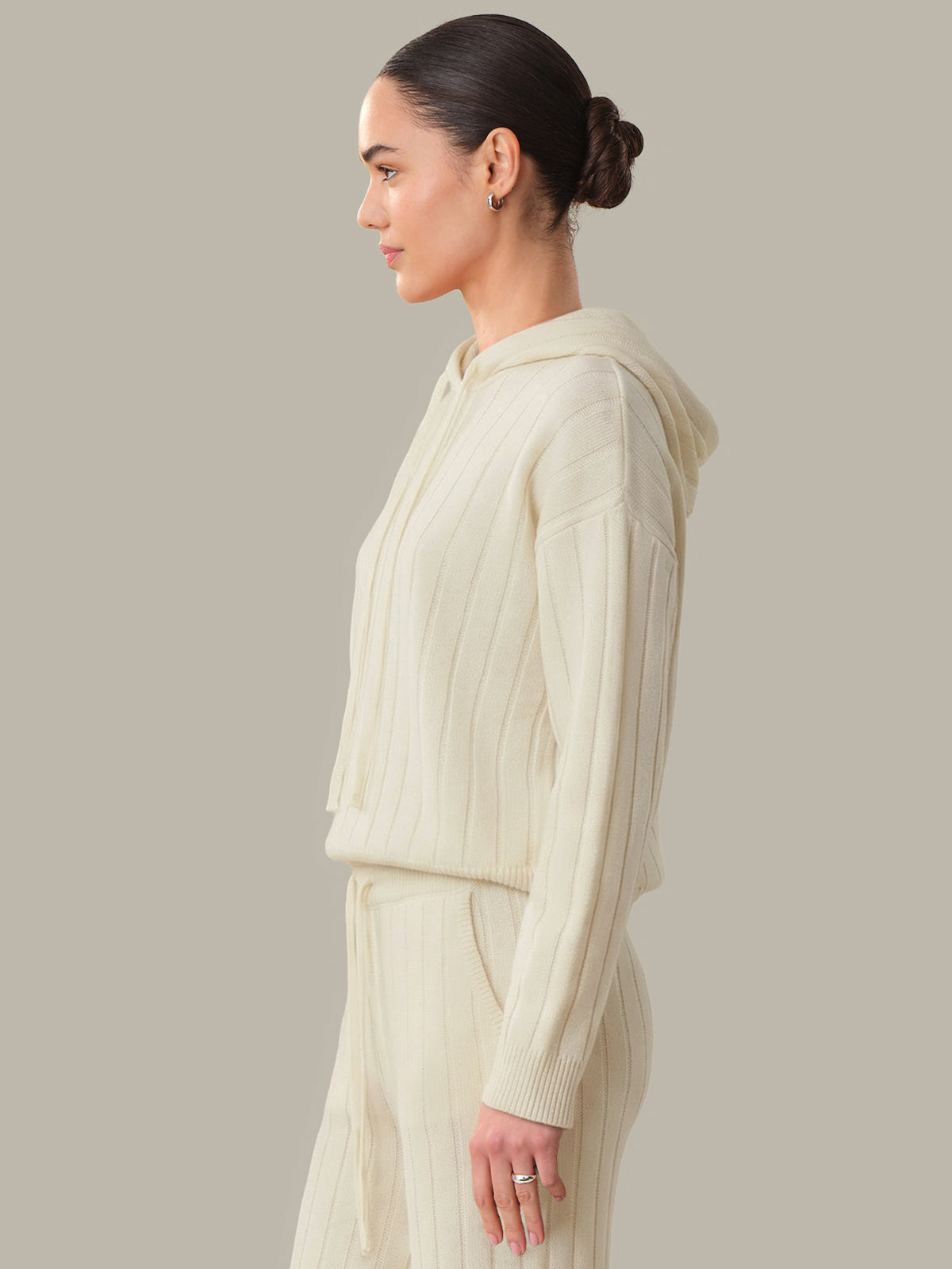 Woman wearing a cream-colored knit outfit against a neutral background