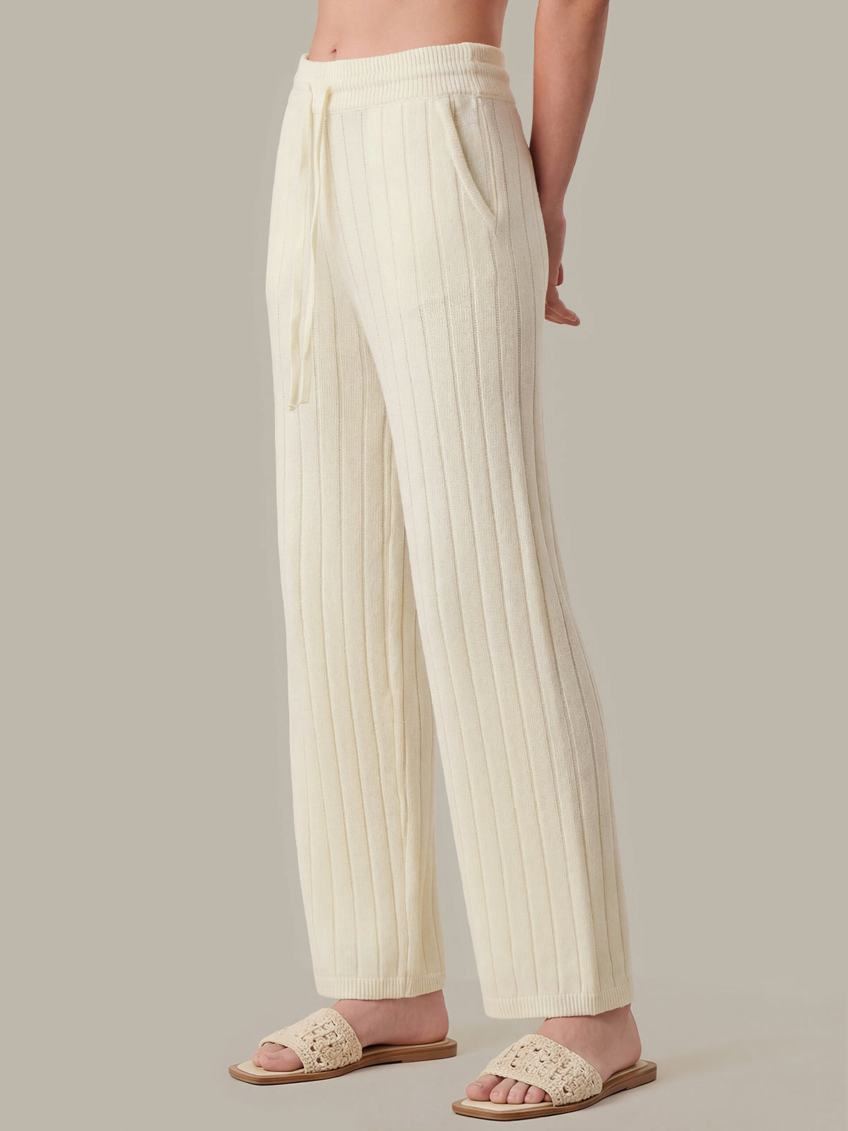 Person wearing cream ribbed knit pants on a plain background