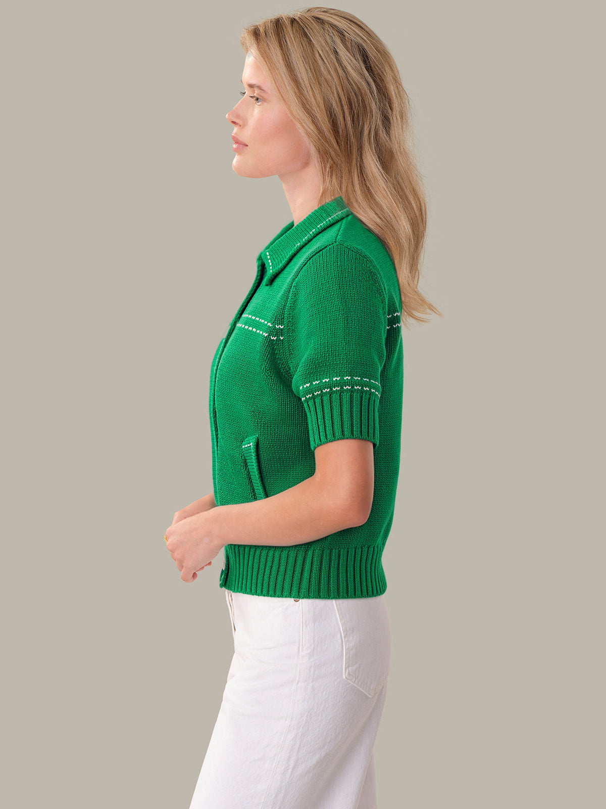 Woman wearing a green knitted cardigan against a gray background