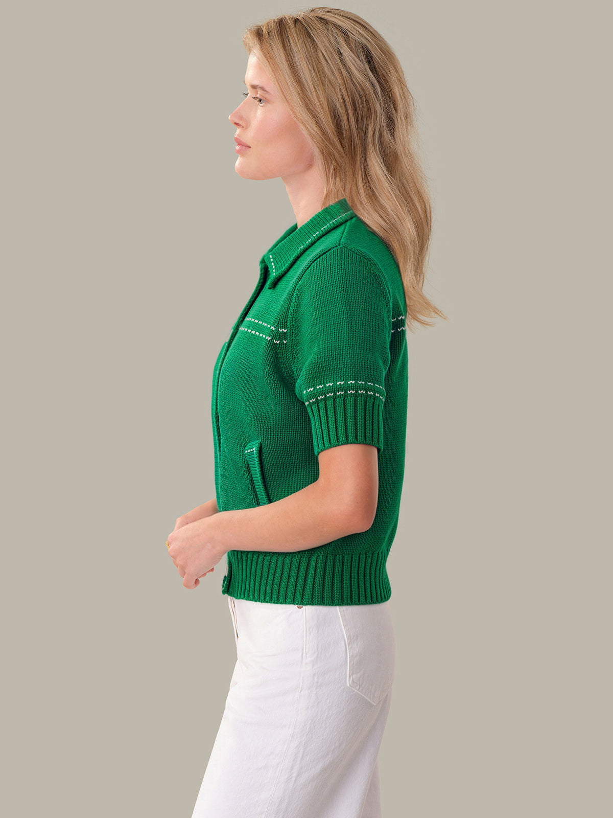 Woman wearing a green knitted cardigan against a gray background