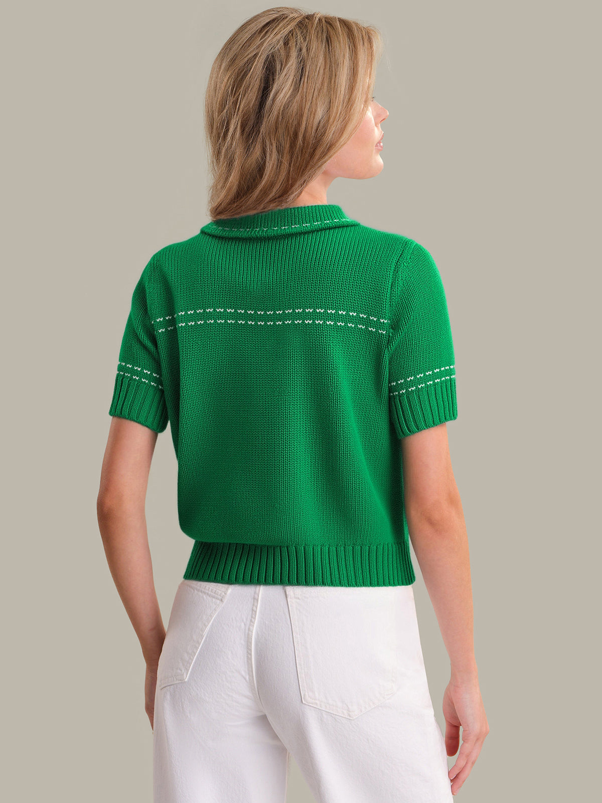 Person wearing a green short-sleeve sweater with white accents on a neutral background