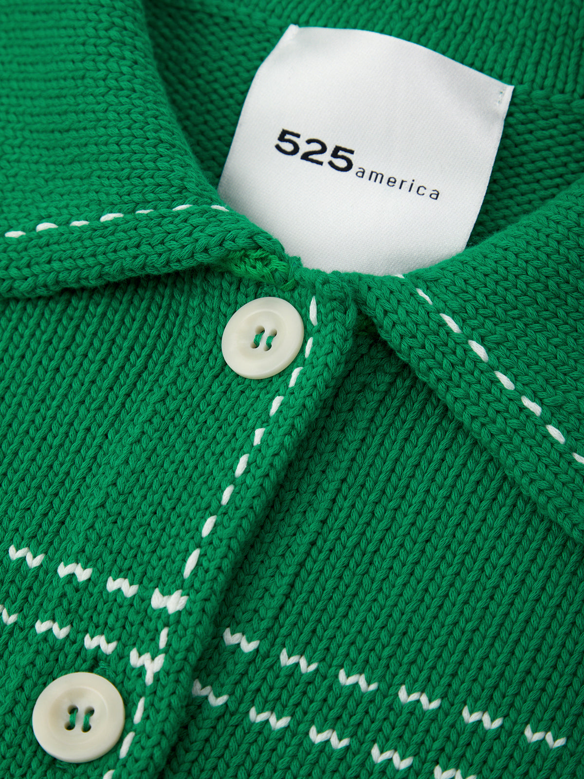Close-up of a green knitted garment with a white label displaying '525 america'.