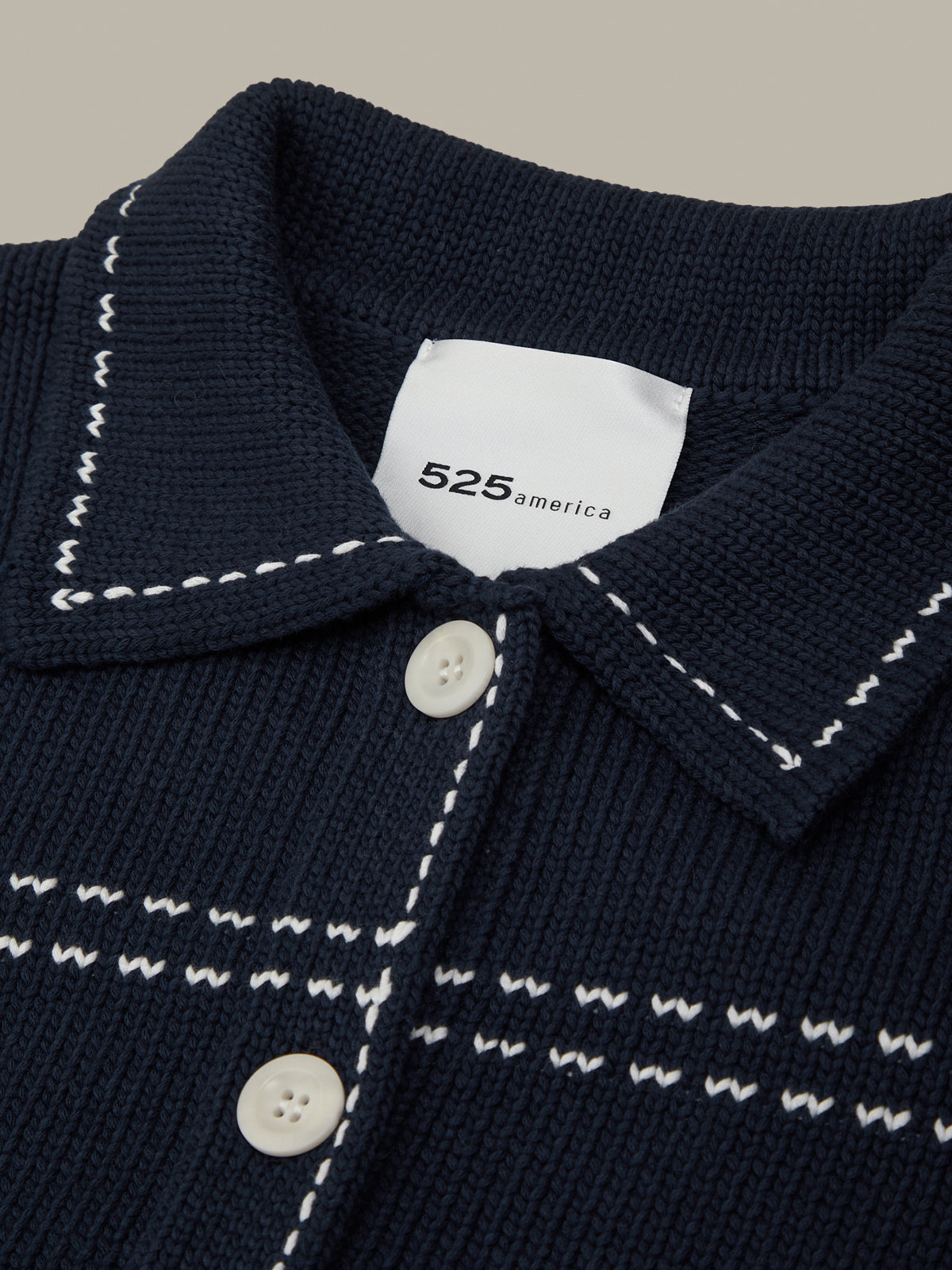 Navy blue garment with white stitching and buttons, featuring a brand label.