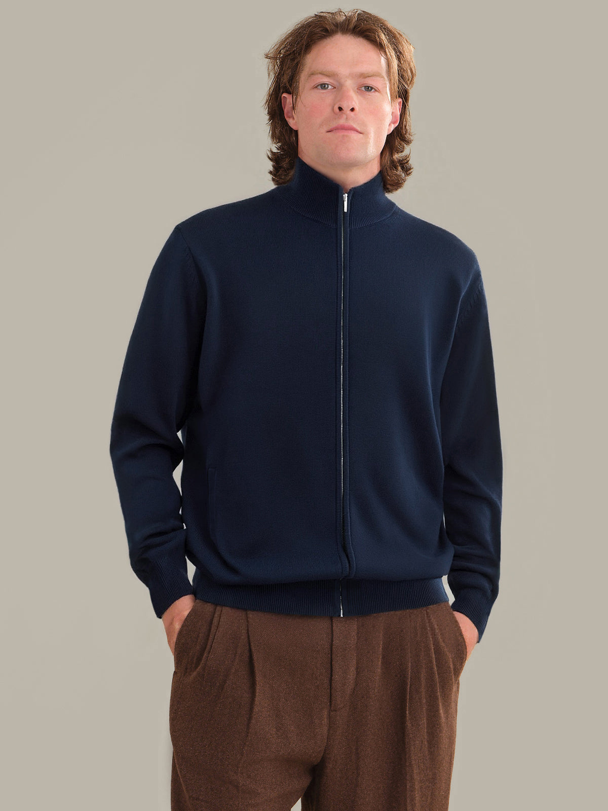 Man wearing a navy blue zip-up sweatshirt against a plain background