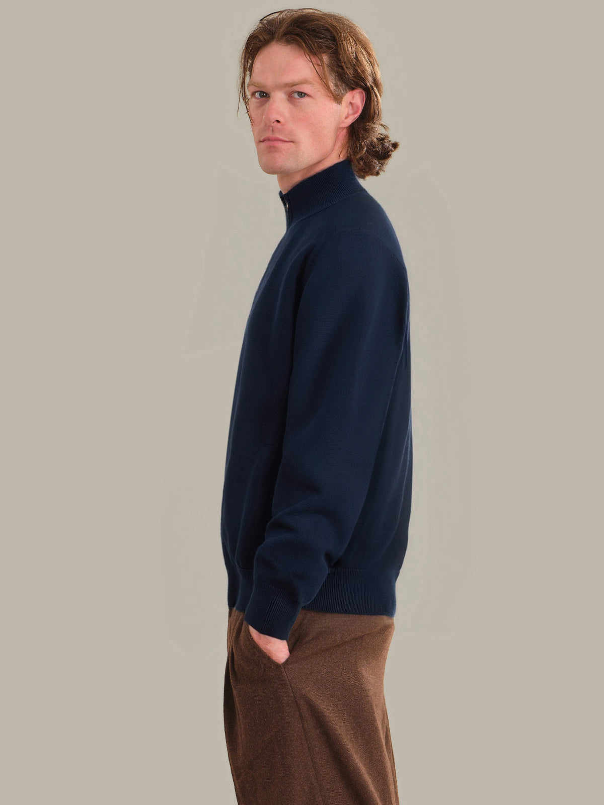 Man wearing a navy blue sweater against a plain background