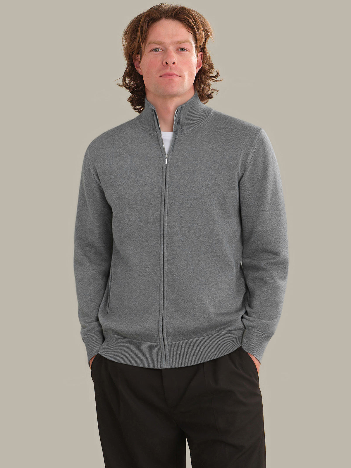 Man wearing a gray zip-up sweatshirt against a plain background