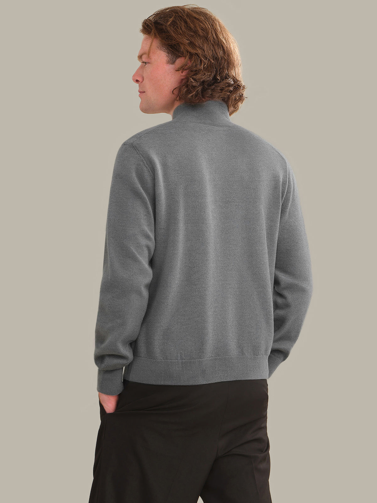 Person wearing a gray sweater against a plain background