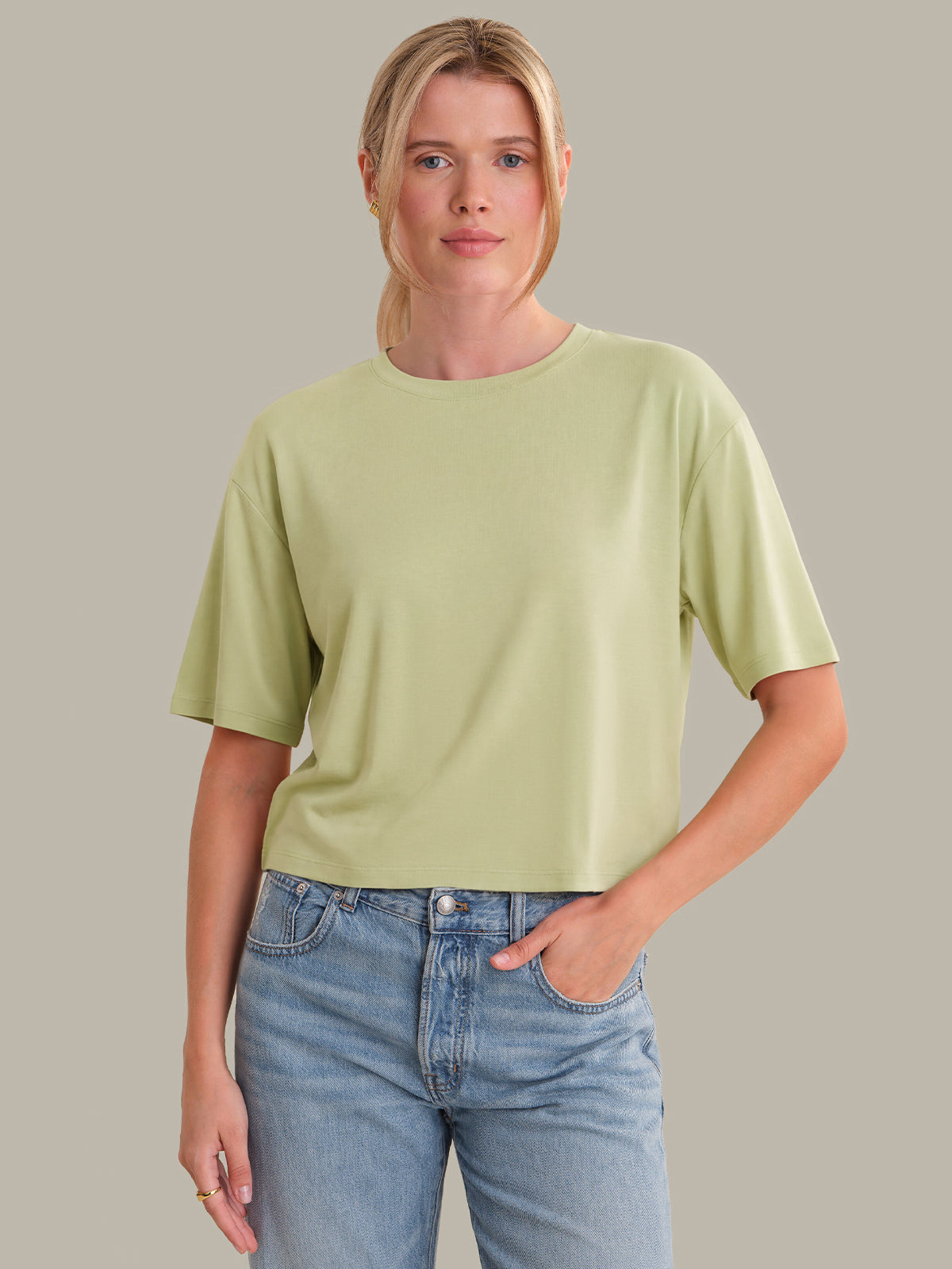 Person wearing a light green t-shirt and blue jeans against a plain background