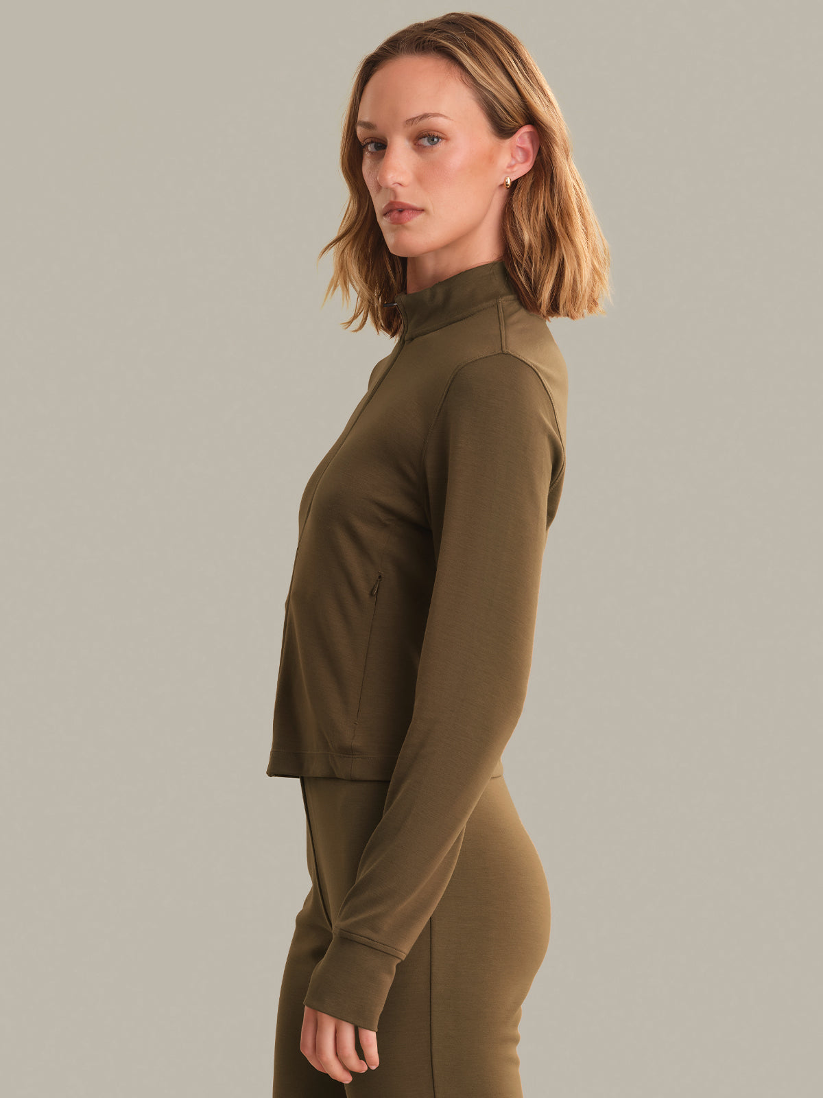 Woman wearing a brown long-sleeve top against a gray background