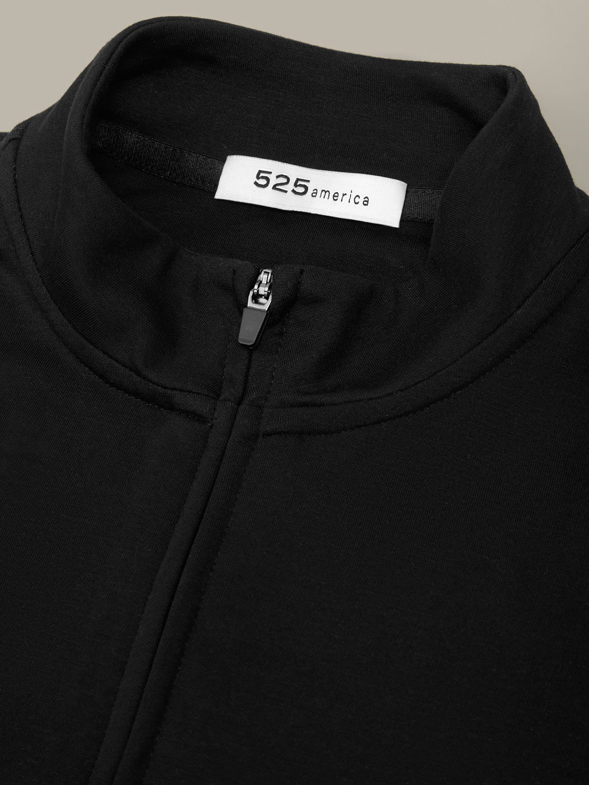 Close-up of a black hoodie with a visible brand label on a neutral background
