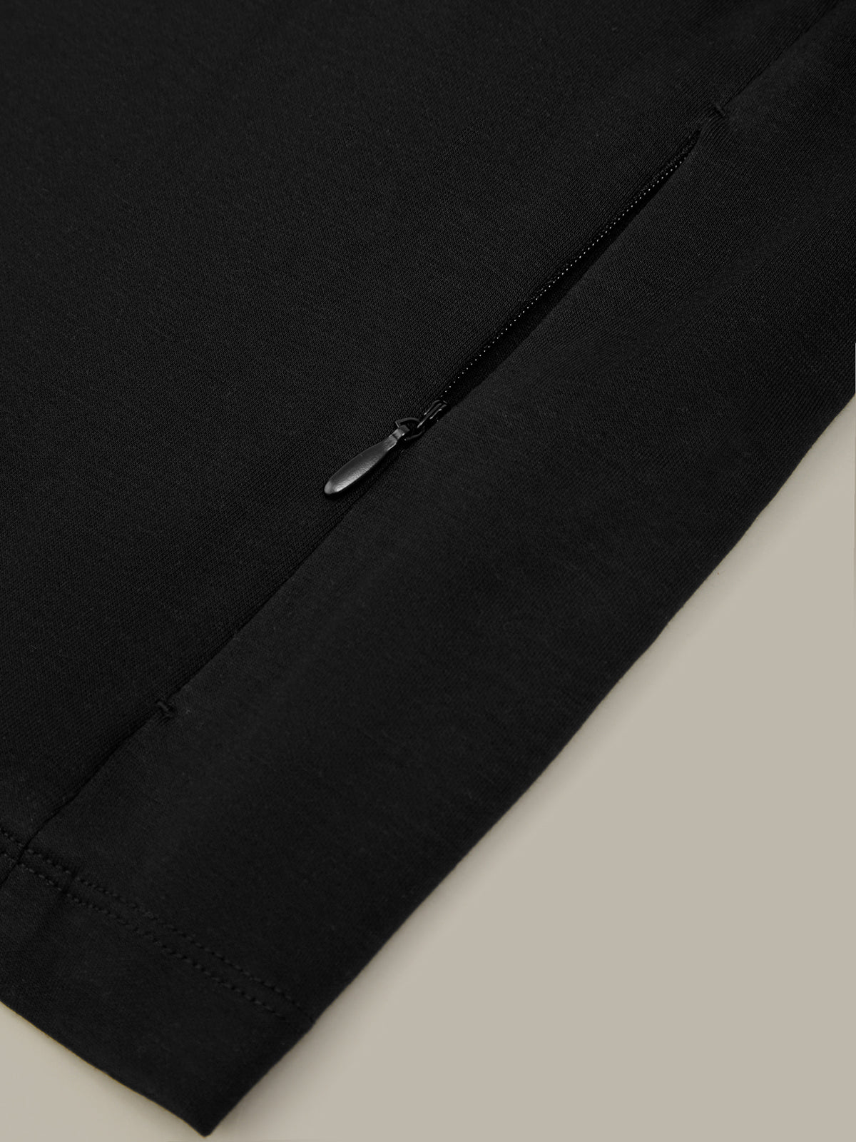 Black pants with a zipper on a light beige background