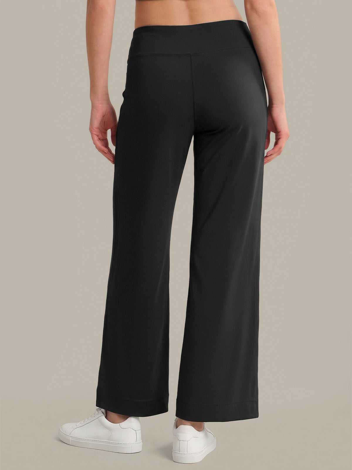 Person wearing black wide-leg pants on a beige background