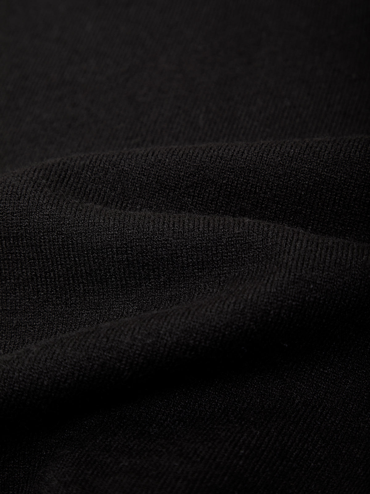 Close-up of a black ribbed knit fabric with soft folds showing the texture and weave.