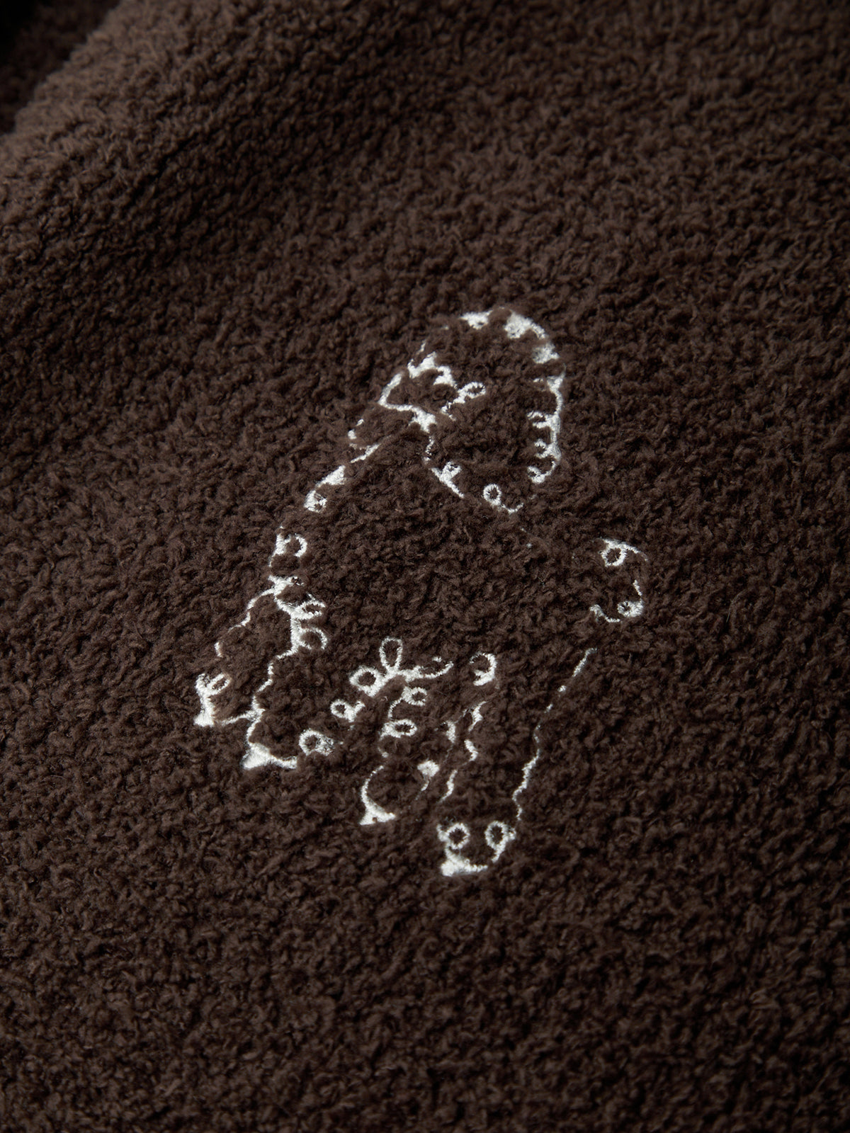 Embroidered lizard design on a brown fabric background