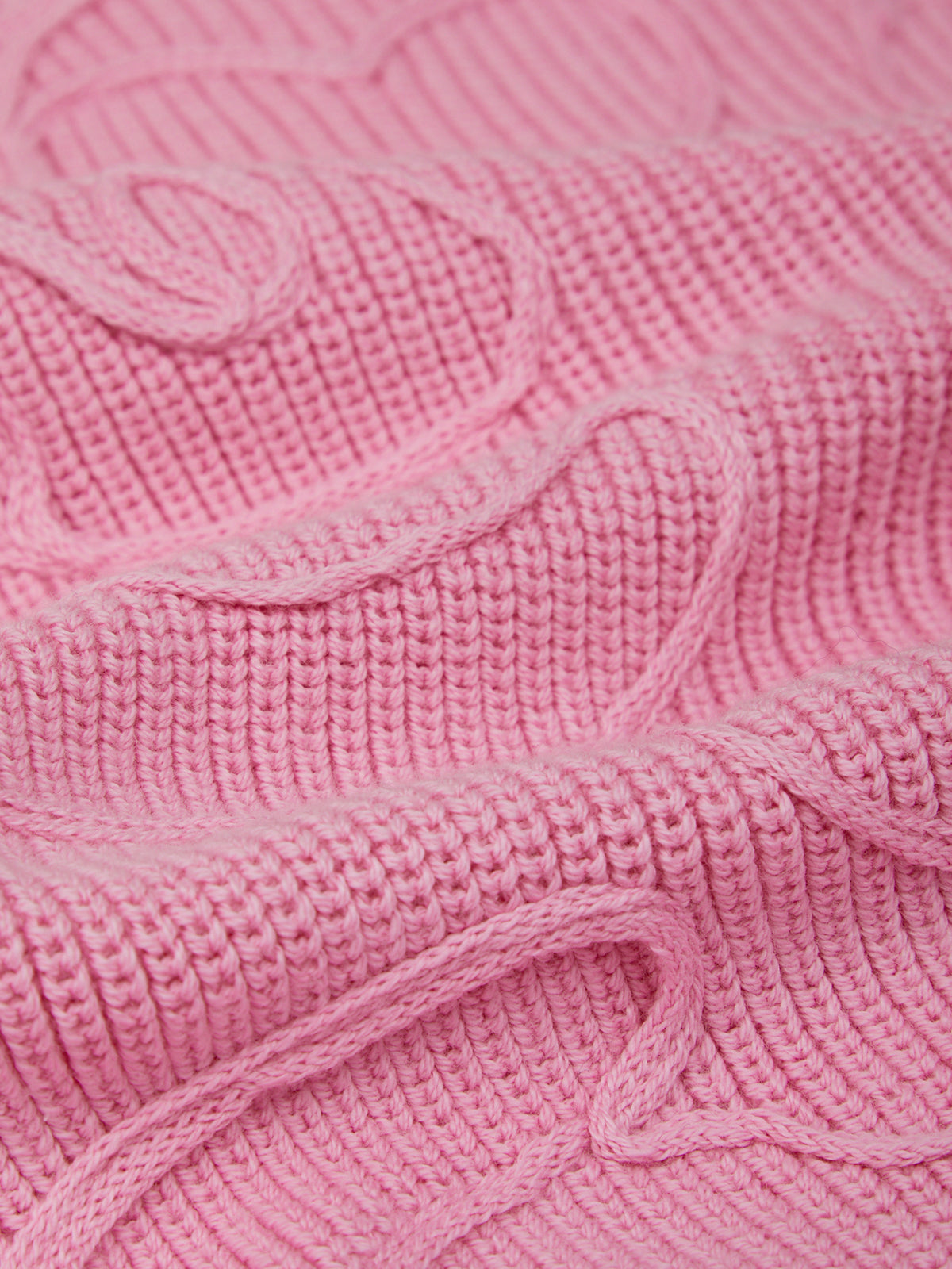 Close-up of a pink knitted fabric with cable pattern