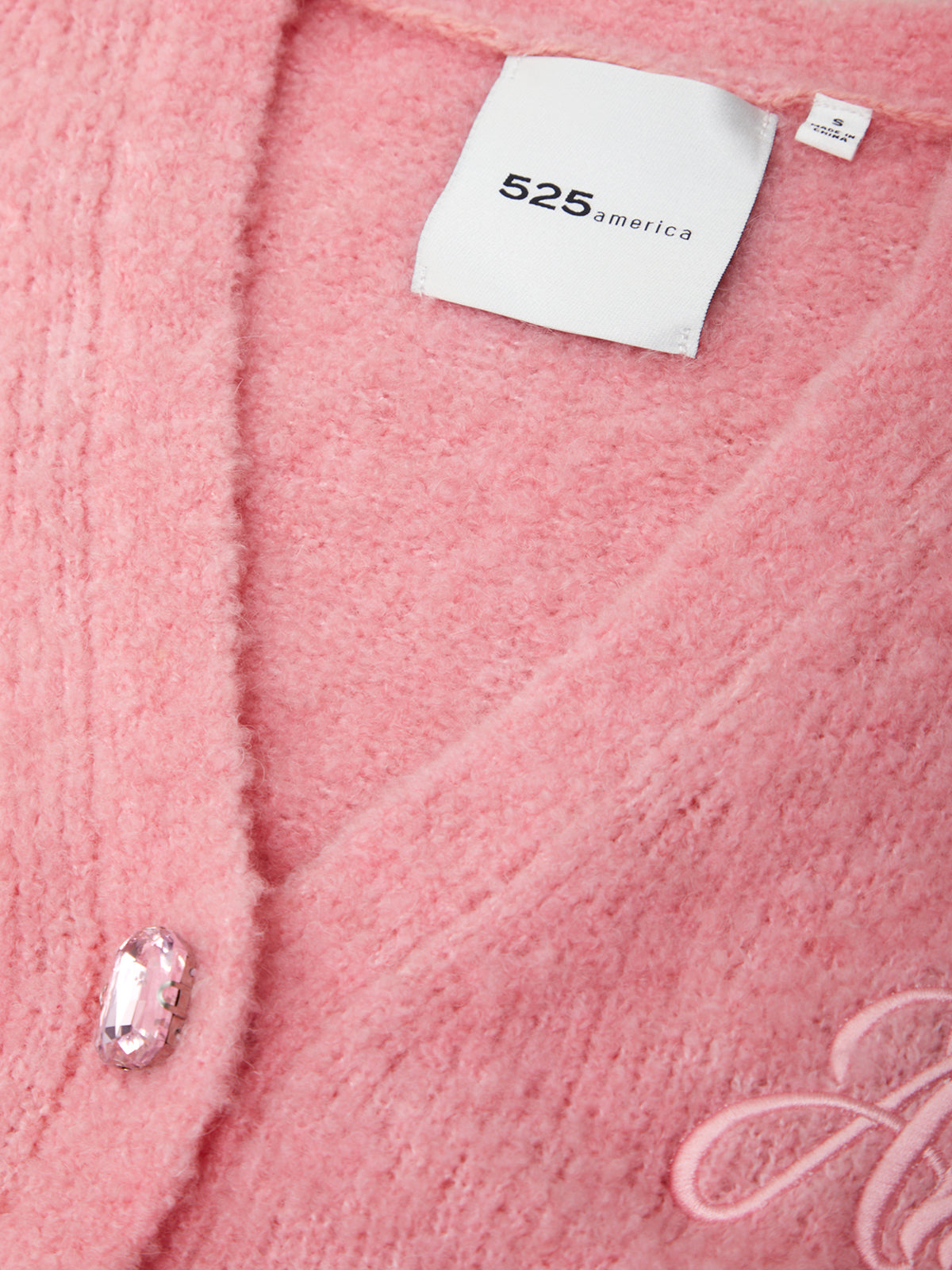 Close-up of a pink textured fabric with a brand tag and logo.