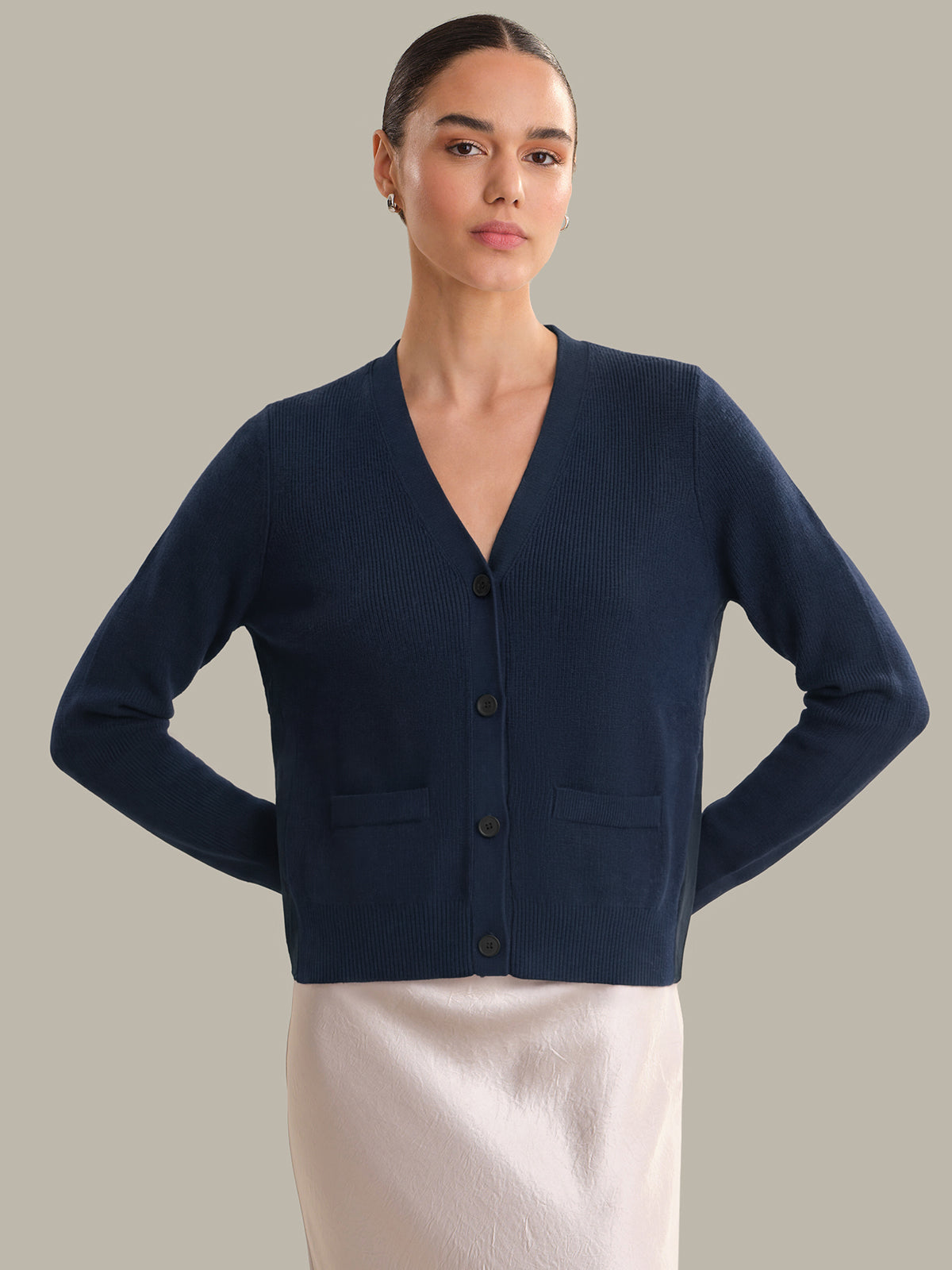 Woman wearing a navy blue cardigan against a plain background