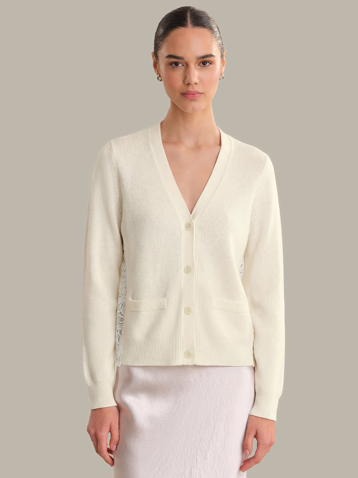 Woman wearing a light-colored cardigan against a neutral background