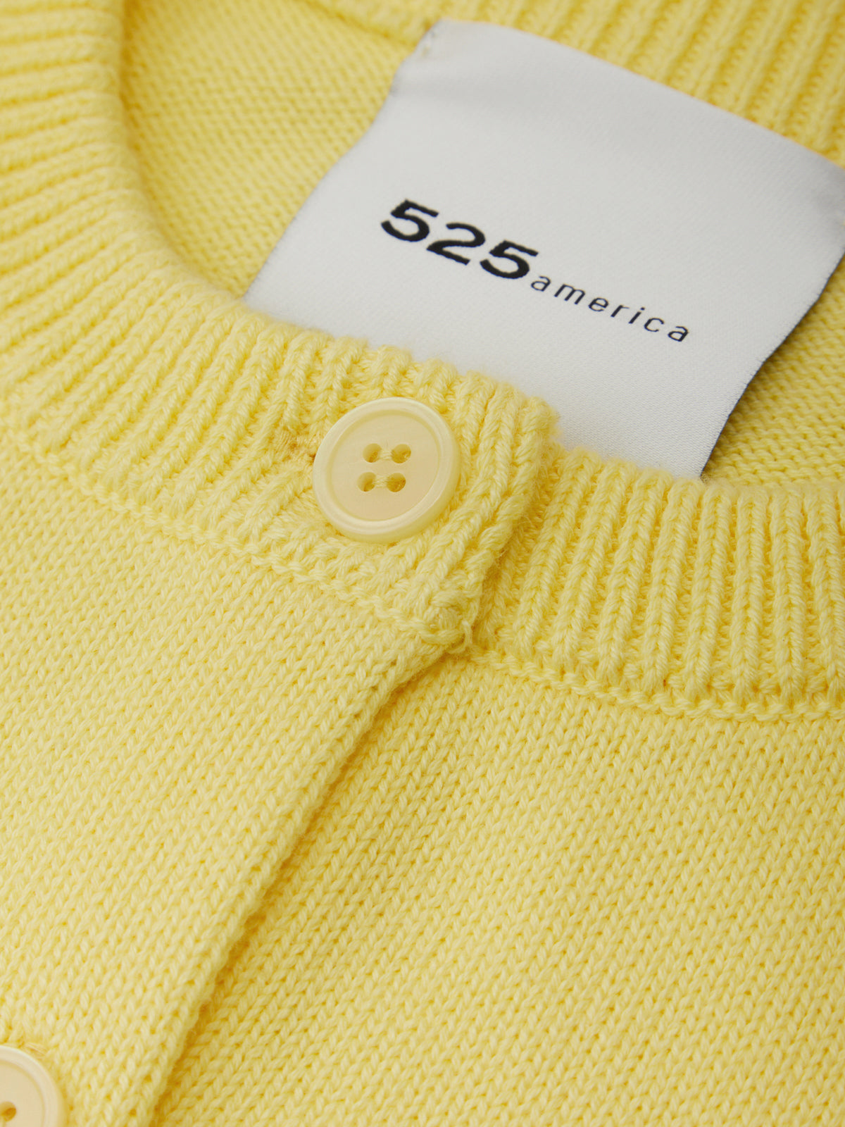 Yellow knitted garment with a button and '525 america' label.