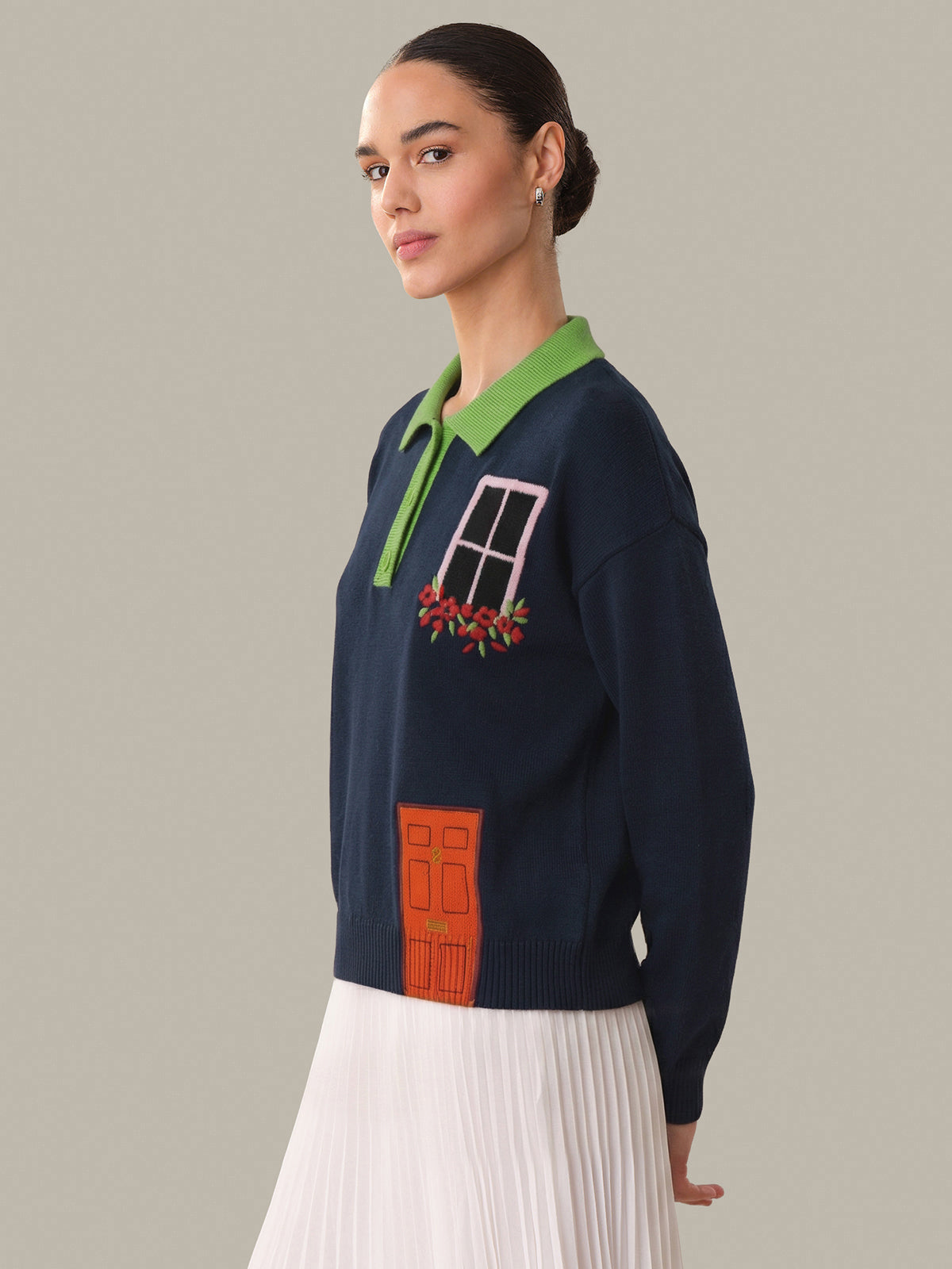 Woman wearing a navy sweater with colorful design elements on a gray background