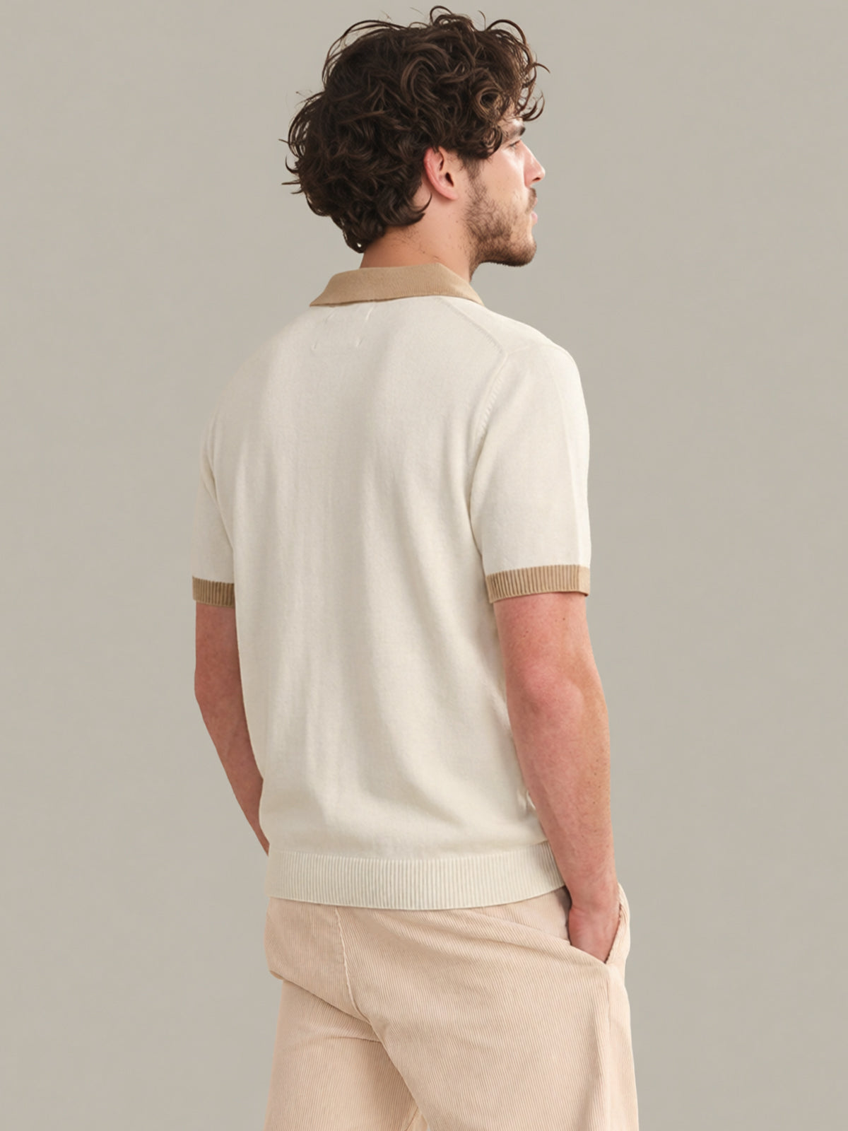 Man wearing a cream-colored polo shirt with beige accents on a plain background