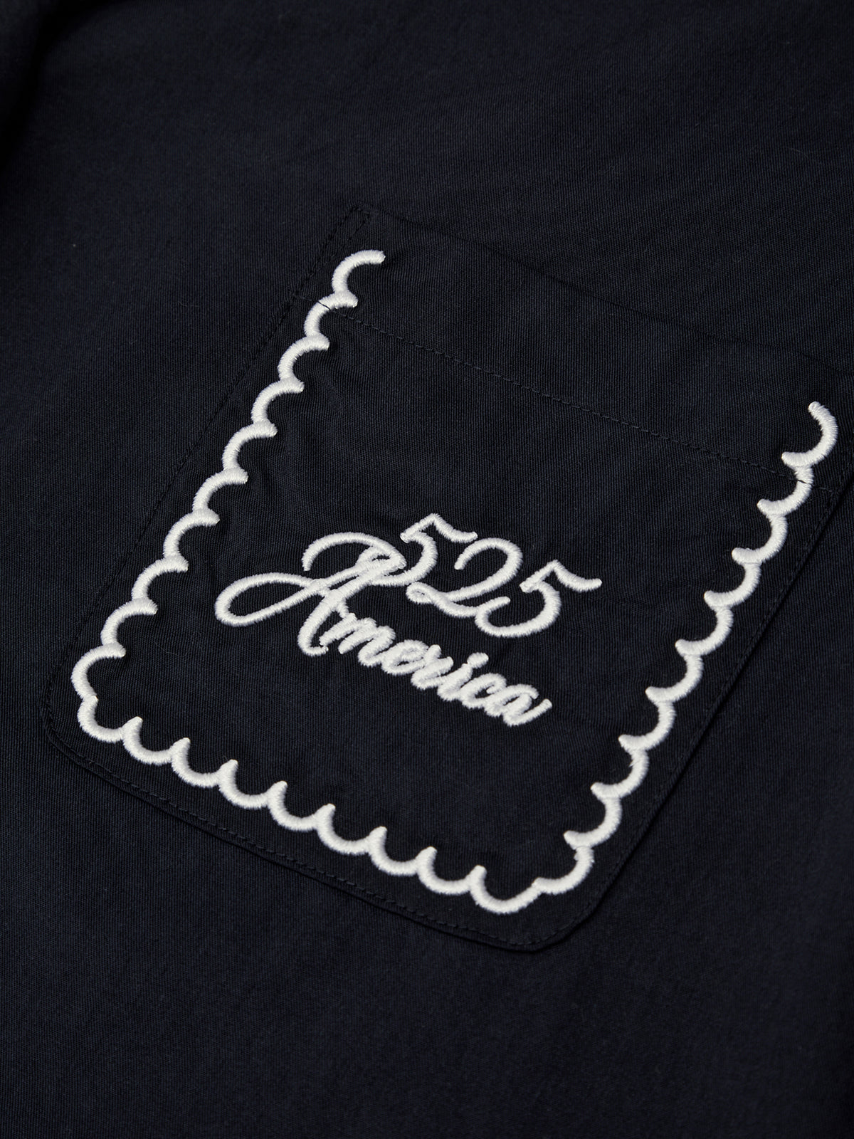 Black fabric with white embroidered design featuring '525 America' text on a dark background