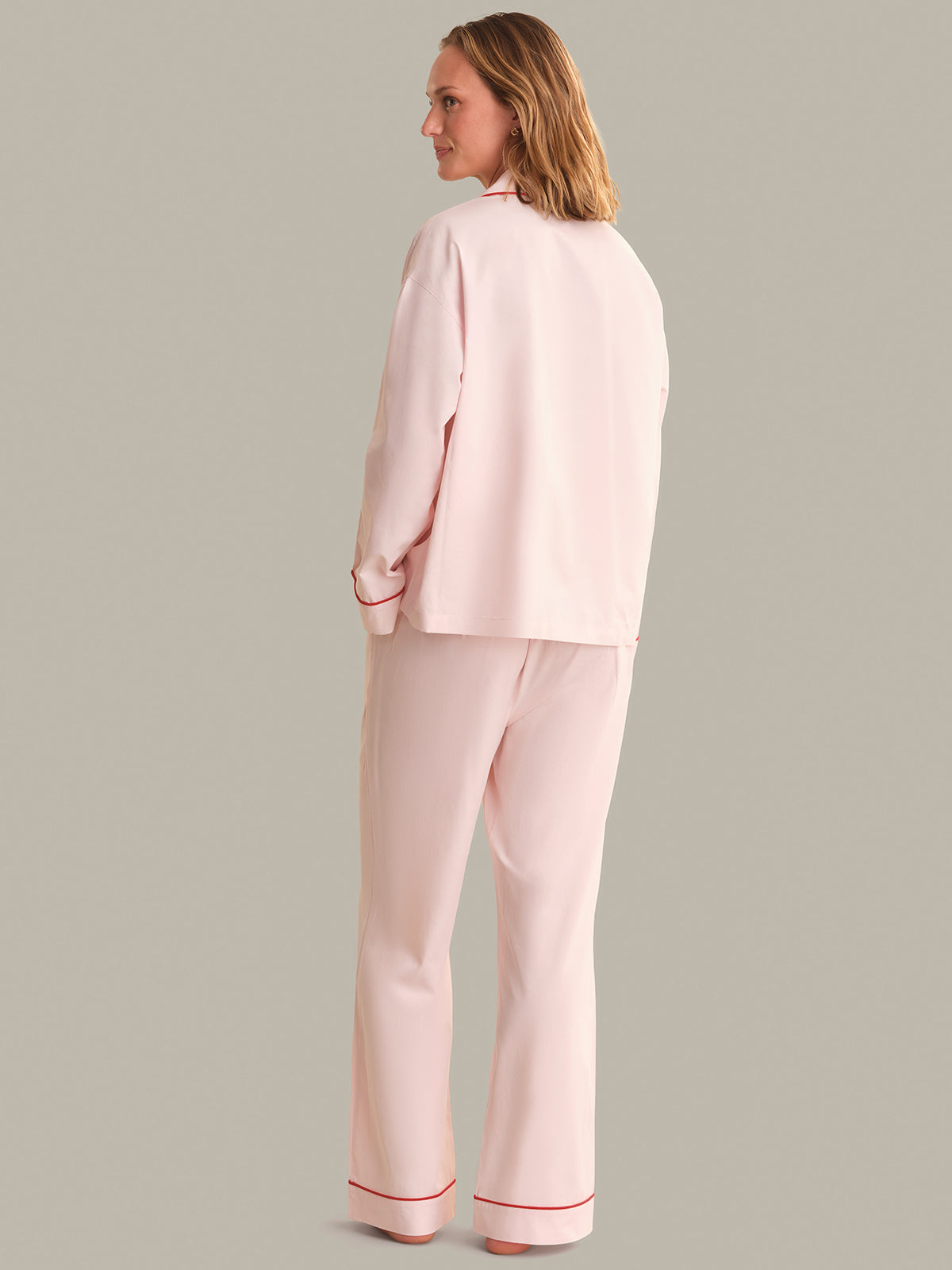 Woman wearing a light pink pajama set on a gray background
