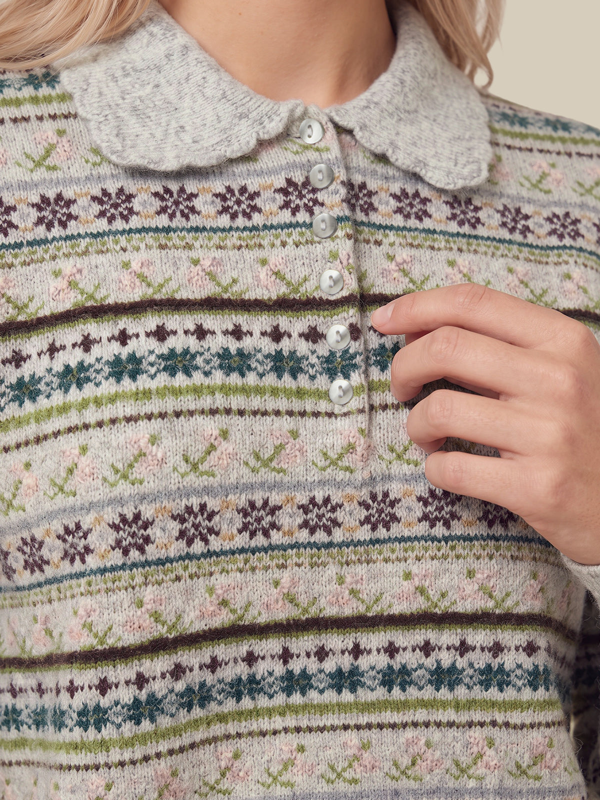 Close-up of a person wearing a knit polo-style sweater with a gray Peter Pan collar and a multicolor Fair Isle pattern in beige, green, blue, and brown.