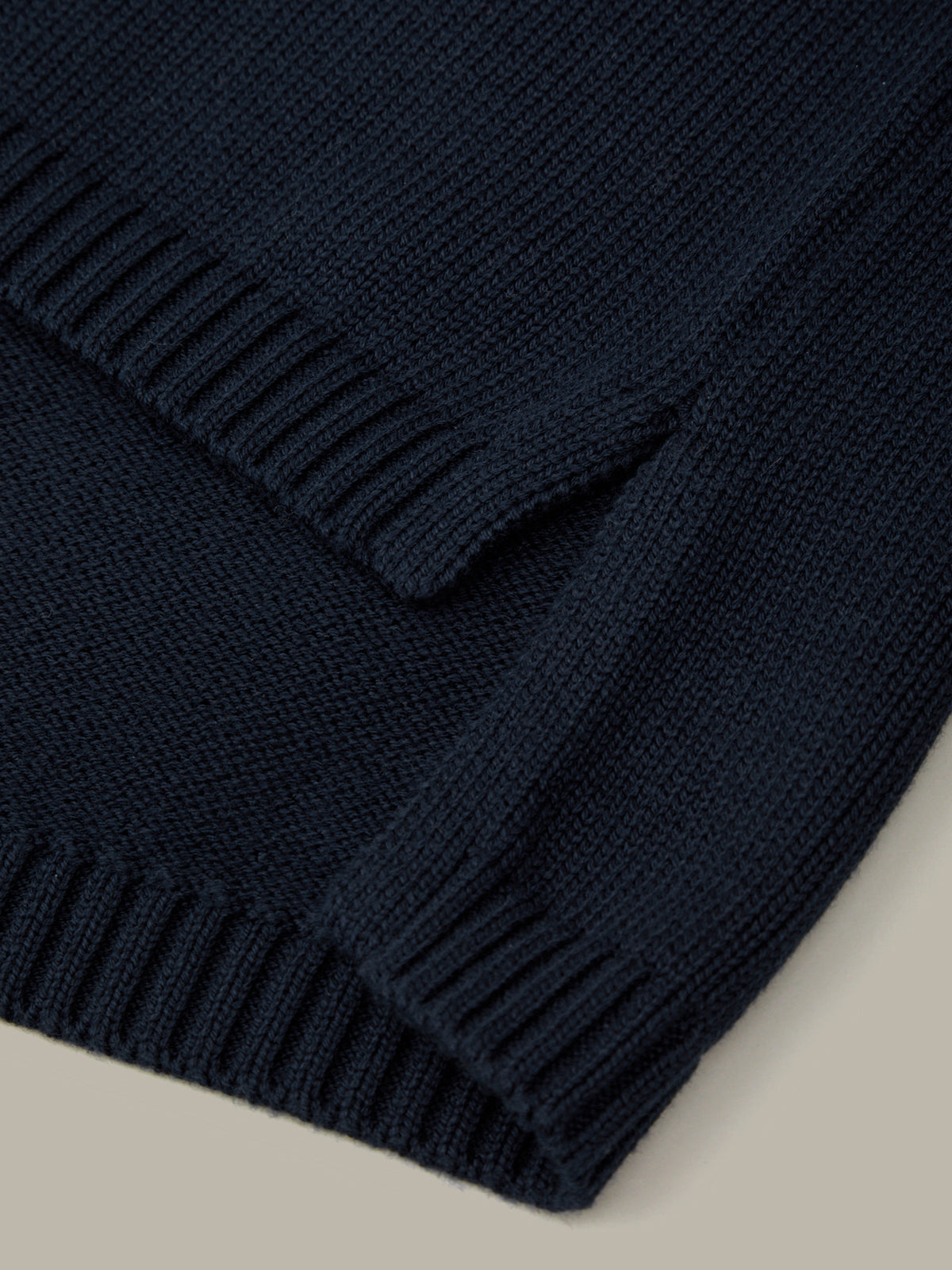 Close-up of a navy blue knitted blanket on a beige surface