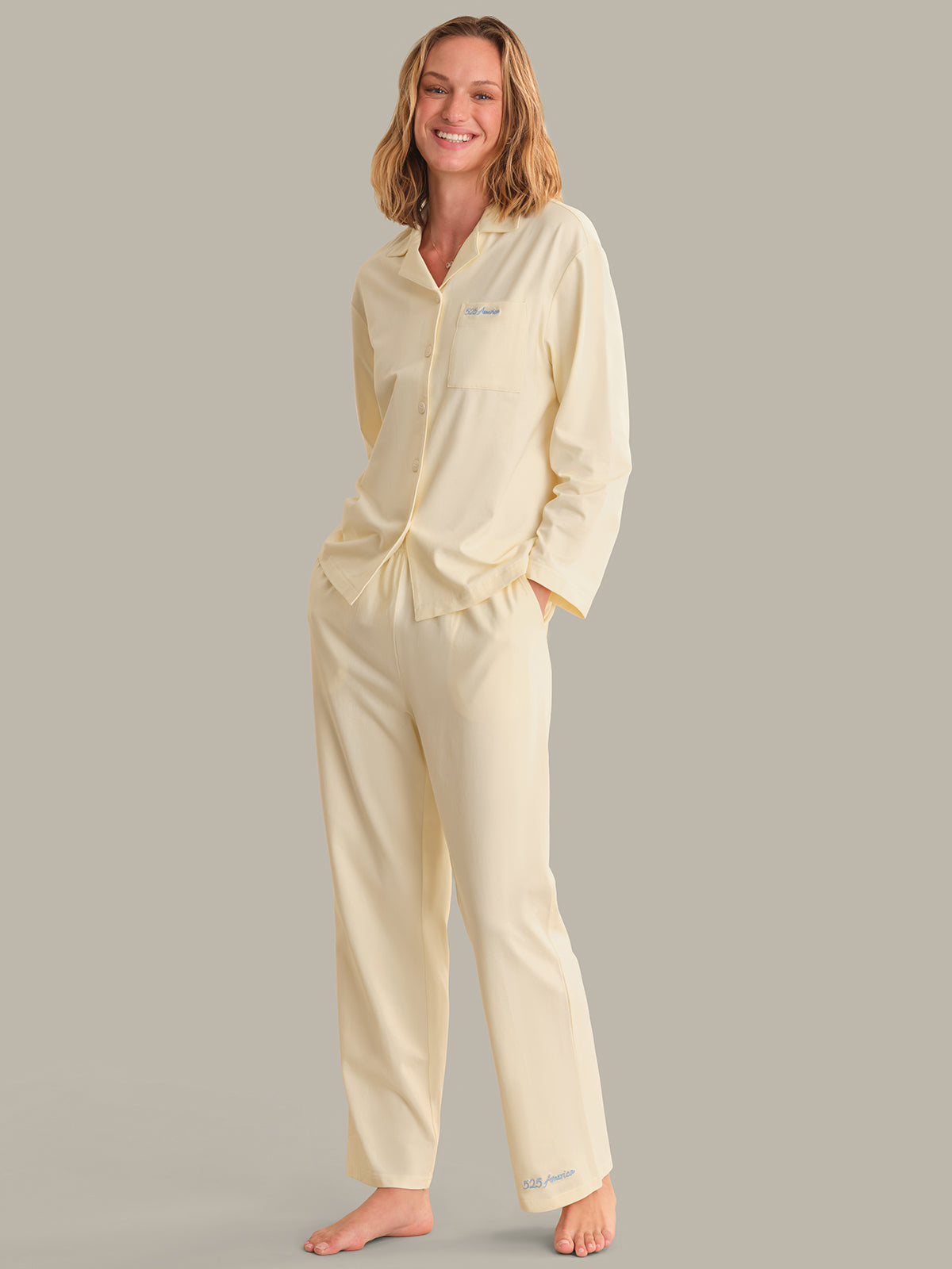 Woman wearing a light yellow pajama set on a gray background