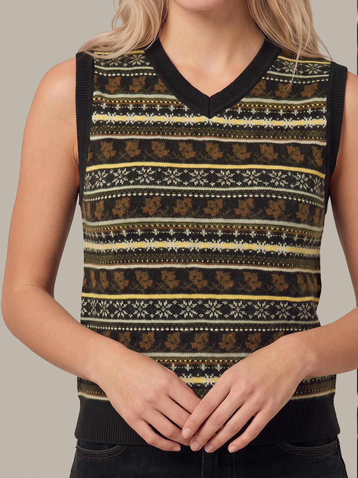 A sleeveless V-neck knit sweater vest with a Nordic-style pattern in black, mustard yellow, and brown, worn by a model.