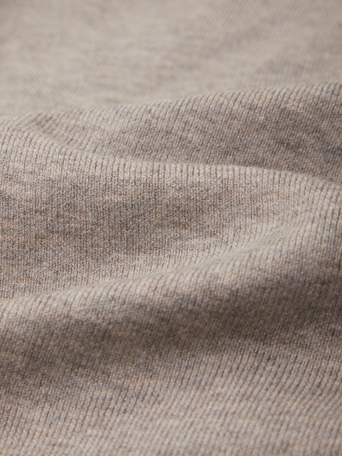 Close-up of a ribbed knit fabric in a warm taupe-beige color, showing the texture and weave detail.