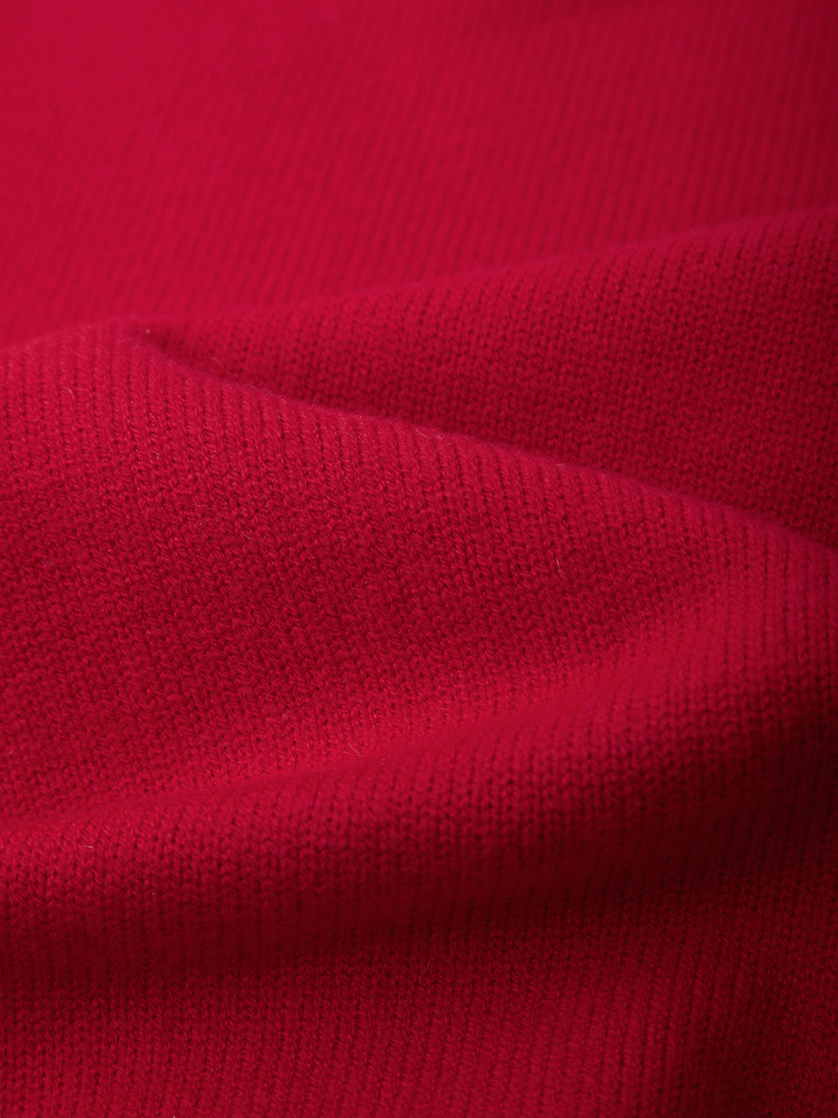 A close-up of bright red knit fabric with soft folds showing the texture and weave.