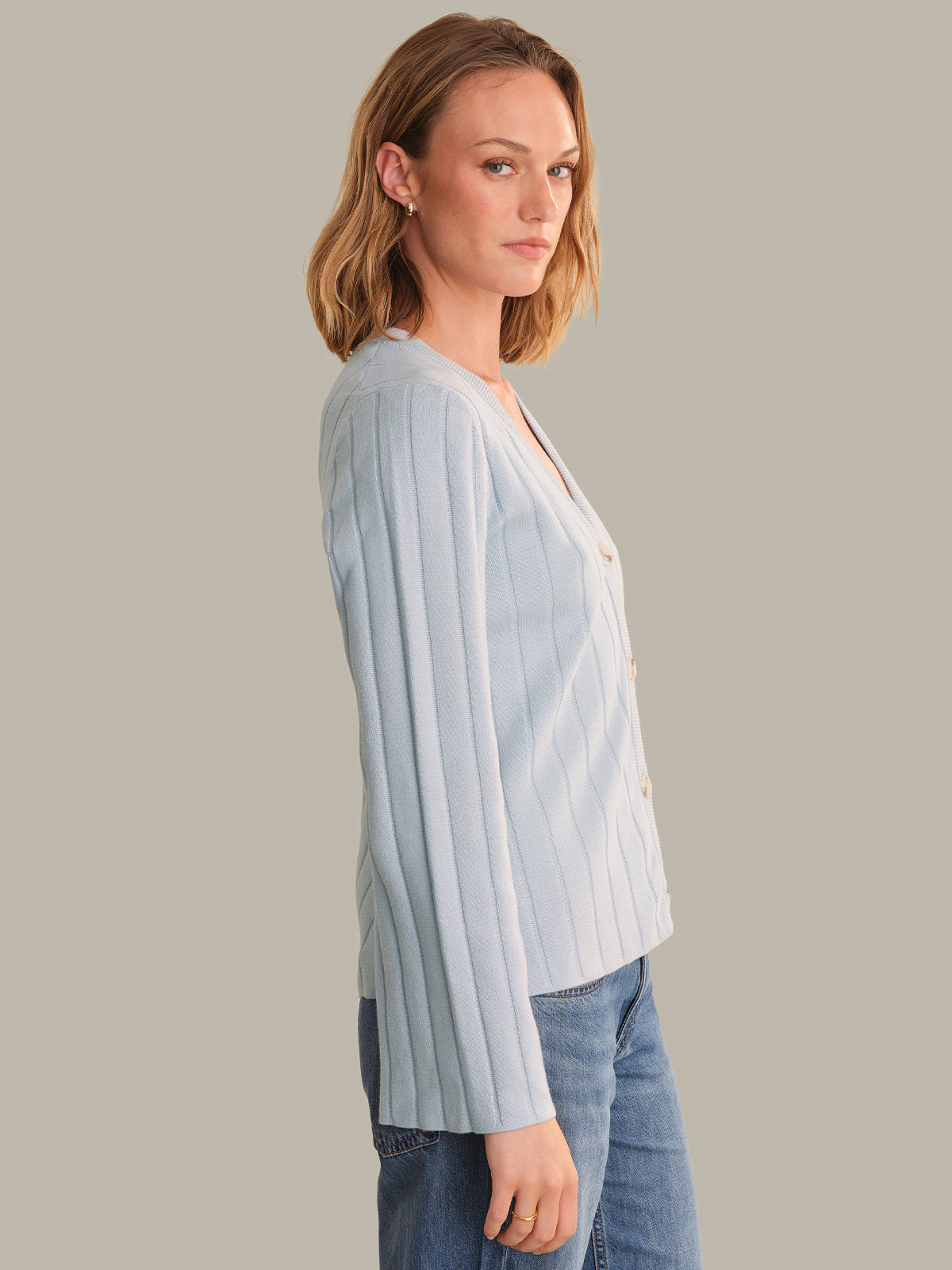 Woman wearing a light blue striped shirt and jeans on a gray background