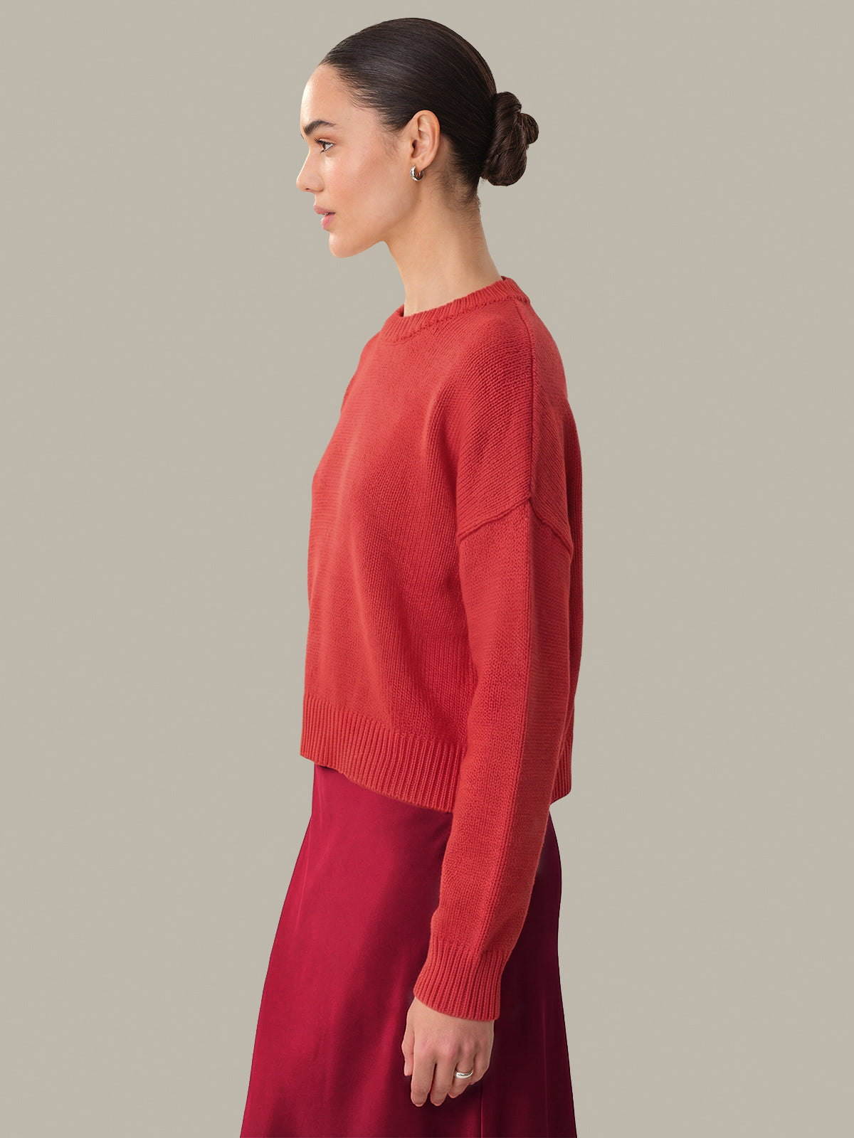 Woman wearing a red sweater and red pants against a neutral background