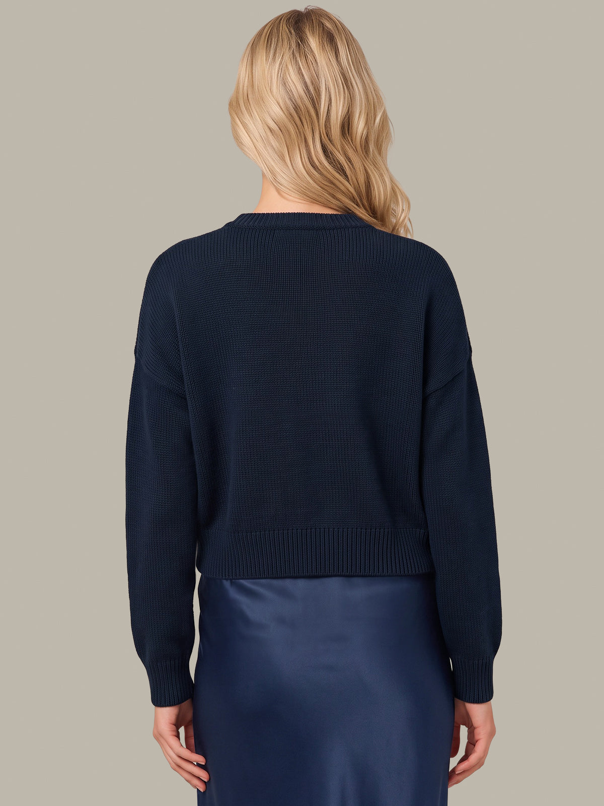 A woman shown from the back wearing a dark navy ribbed knit cropped sweater and a matching dark navy skirt, against a solid light gray background.