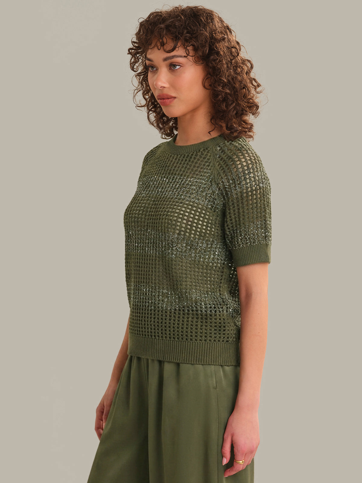 Woman wearing a green knitted top against a neutral background