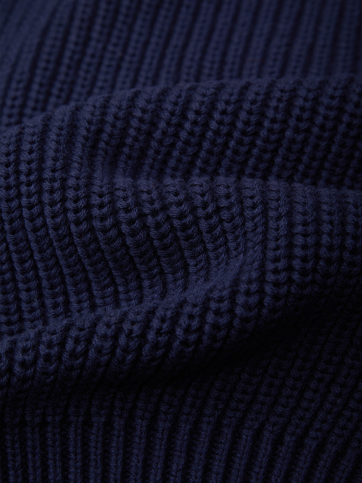 Close-up of a dark navy blue ribbed knit fabric texture with soft folds.