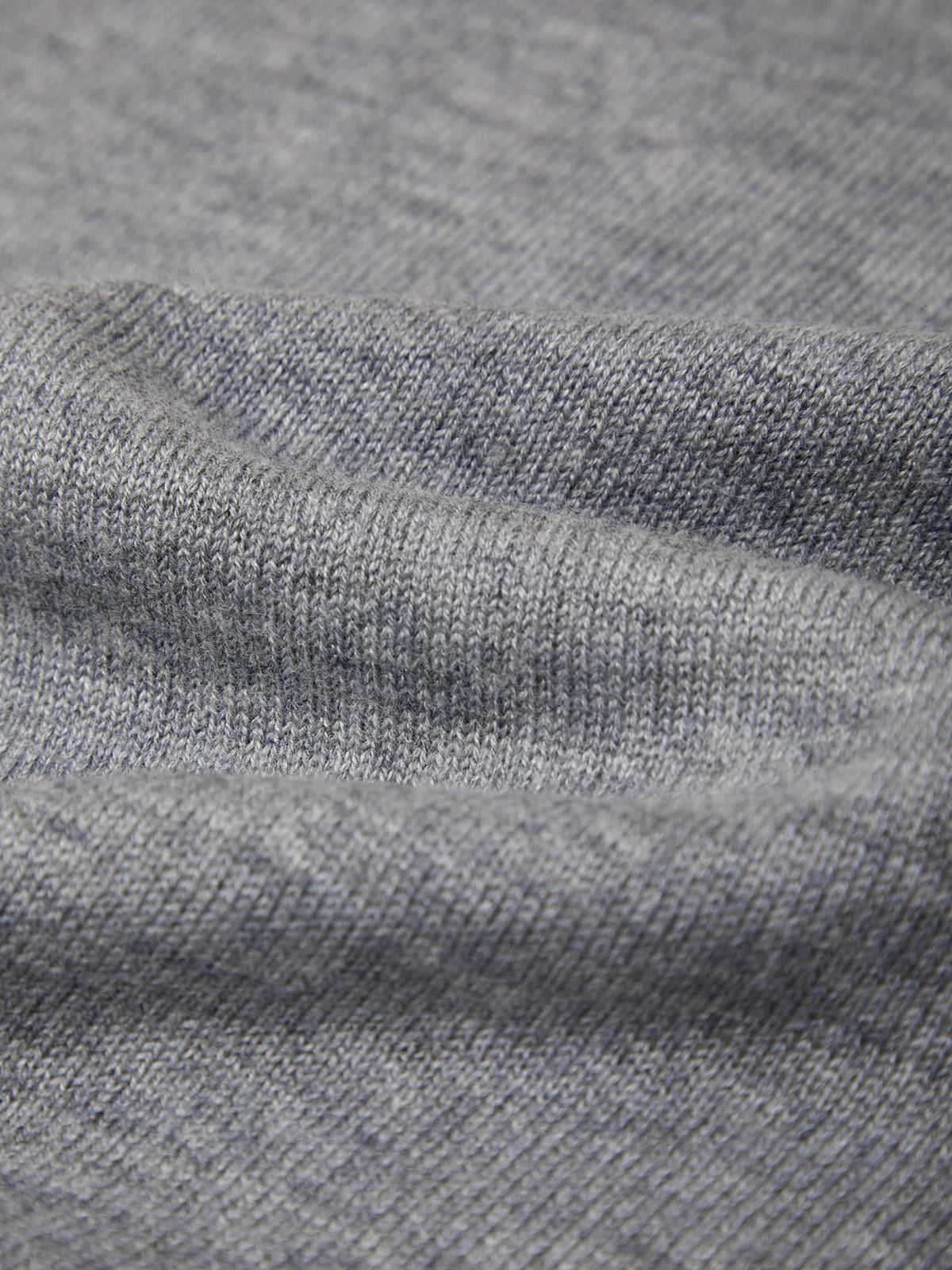 Close-up of a heather gray knit fabric texture with soft folds and ribbed stitching.