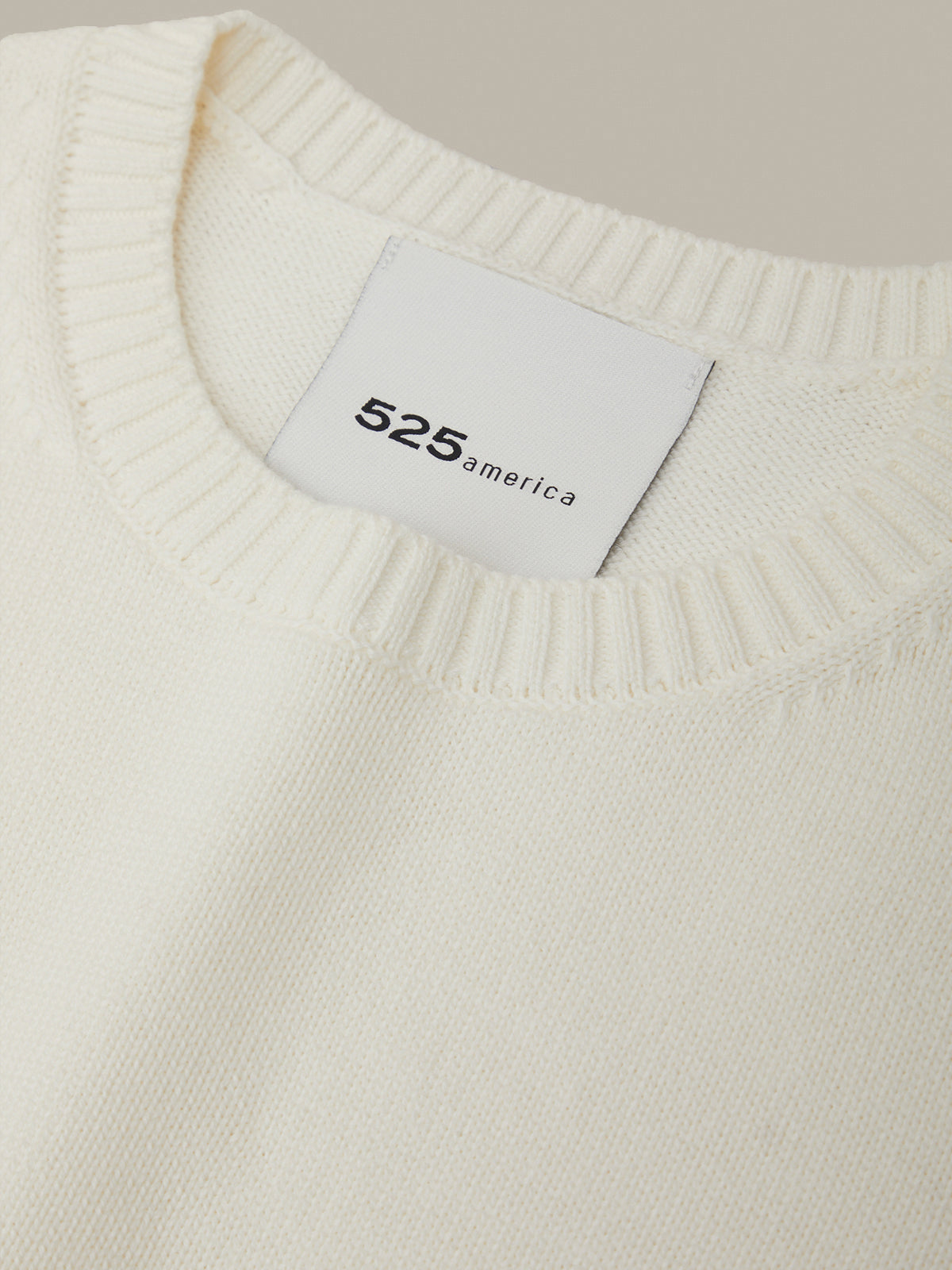 Close-up of a white sweater with a '525 america' label.