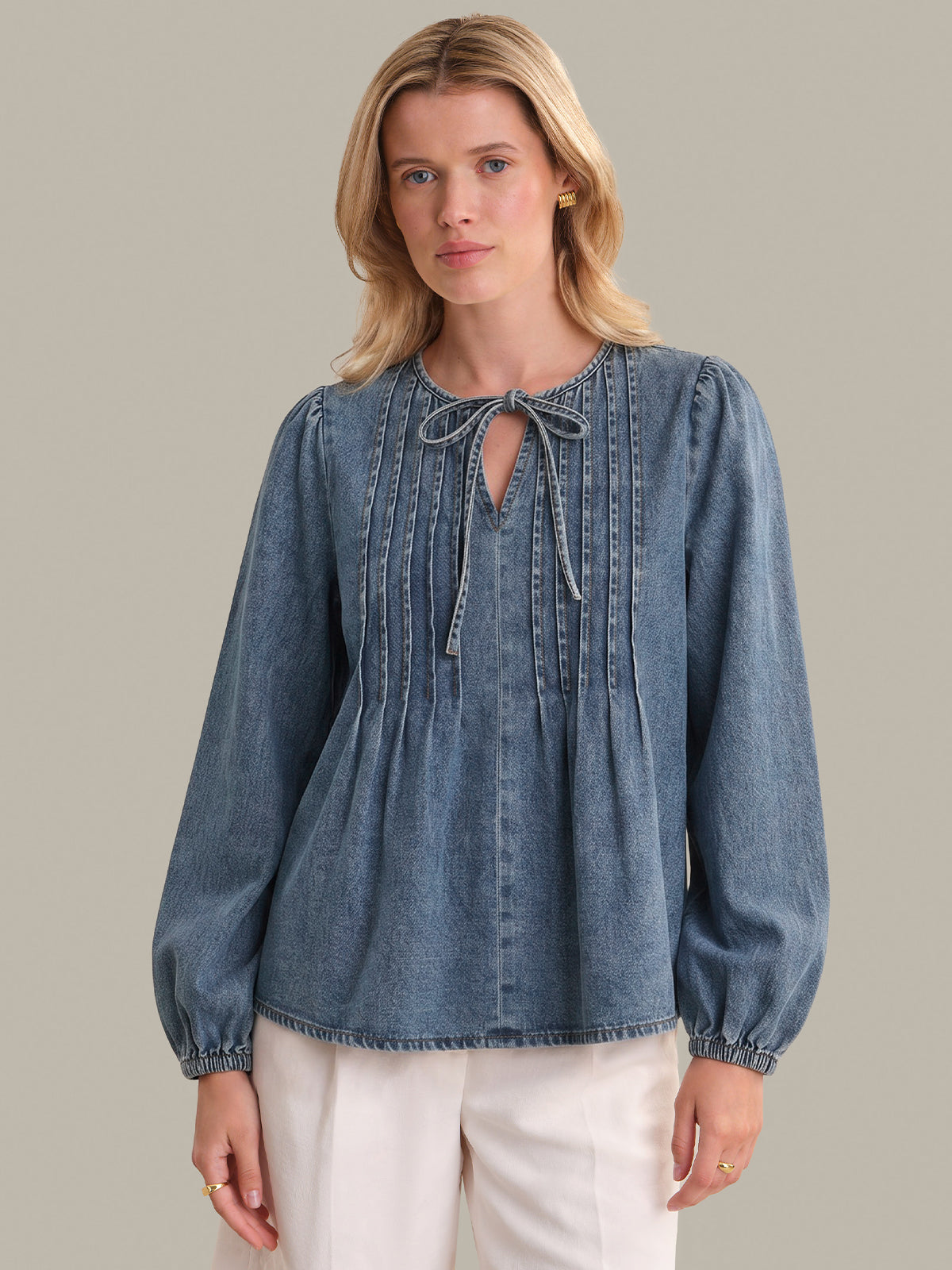 Woman wearing a blue denim blouse with a plain background