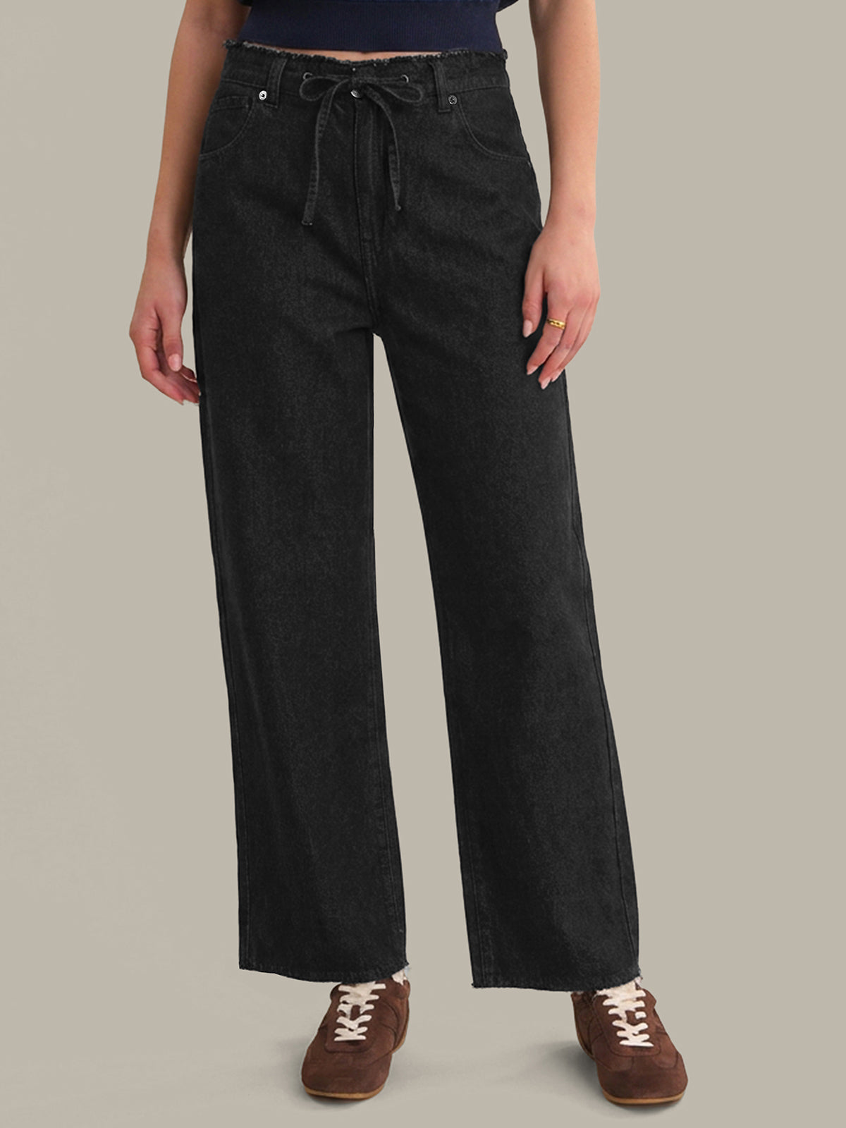 Person wearing black wide-leg pants on a beige background